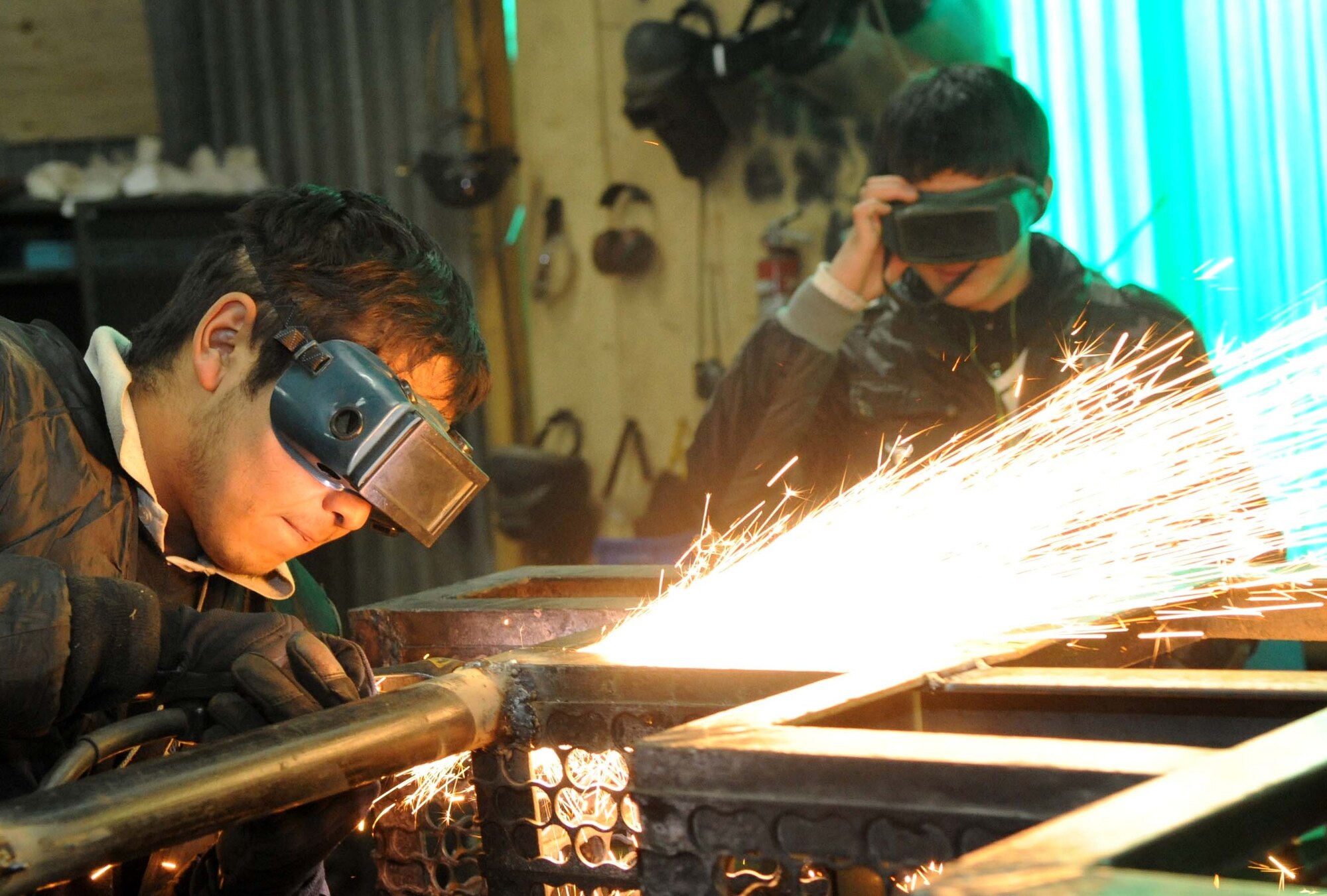 Azat Suerkulov, 376th Expeditionary Civil Engineer Squadron contractor, shows Jeni Jehr Vocational School students from Kyrgyzstan how to weld metal using proper personal protective equipment during their tour of the Transit Center at Manas Feb. 13. These students were touring the 376th ECES to see how Airmen conduct military operations here and learn different civil engineer techniques. (U.S. Air Force photo/Senior Airman Nichelle Anderson/released)