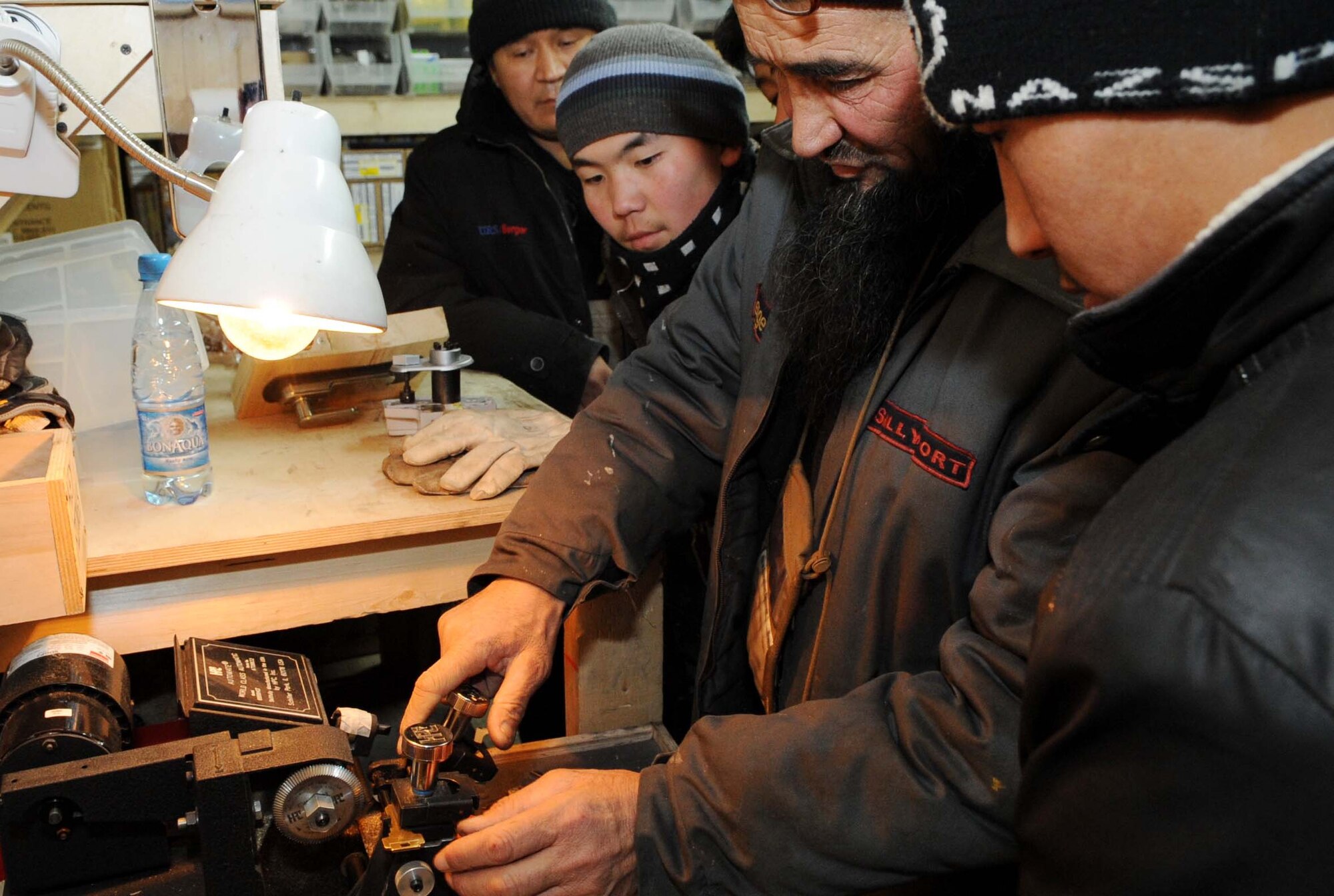 A 376th Expeditionary Civil Engineer Squadron contractor shows Jeni Jehr Vocational School students from Kyrgyzstan how to safely duplicate keys during their tour of the Transit Center at Manas Feb. 13. These students were touring the 376th ECES to see how Airmen conduct military operations here and learn different civil engineer techniques. (U.S. Air Force photo/Senior Airman Nichelle Anderson/released)
