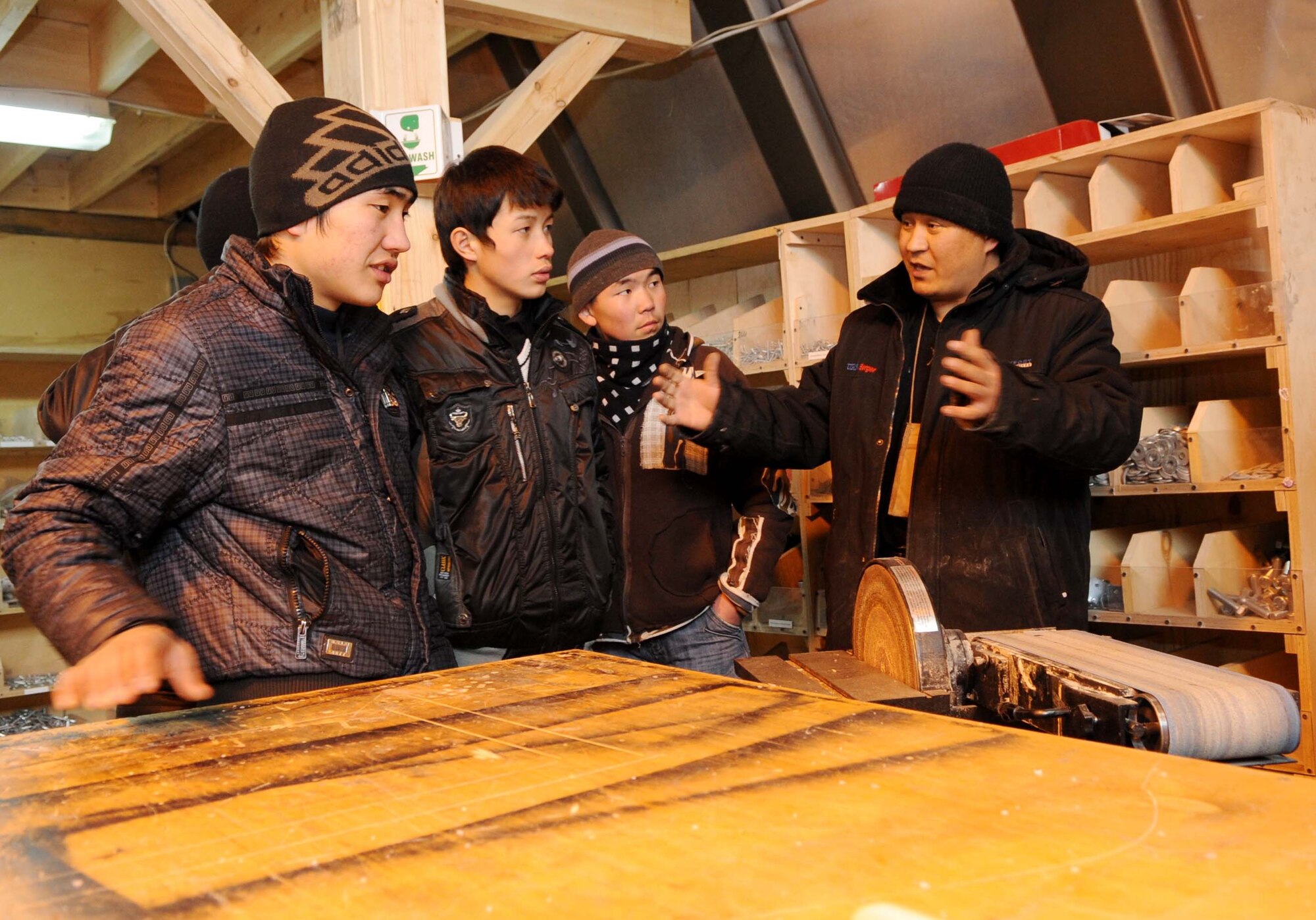 A 376th Expeditionary Civil Engineer Squadron contractor gives Jeni Jehr Vocational School students from Kyrgyzstan a tour of the structures shop during their tour of the Transit Center at Manas Feb. 13. These students were touring the 376th ECES at the Transit Center at Manas, Kyrgyzstan, to see how Airmen conduct military operations here and learn different civil engineer techniques. (U.S. Air Force photo/Senior Airman Nichelle Anderson/released)