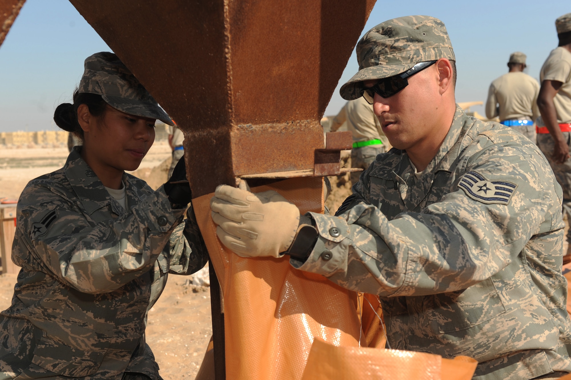 Airman 1st Class Anngerie Lesigues, 379th Expeditionary Logistics Readiness Squadron material management apprentice and Staff Sgt. Aaron Samala, 379th Expeditionary Operation Support Squadron heating ventilation air-conditioning craftsman, fill sandbags as part of a base-wide effort to replace roughly 34,000 deteriorated sandbags at a non-disclosed Southwest Asia location, Feb. 9, 2010. (U.S. Air Force photo by Tech. Sgt. Michelle Larche)[RELEASED]
