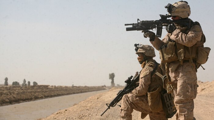 Corporal Jason Ducote, a fireteam leader with 3rd Platoon, India Company, 3rd Battalion, 6th Marine Regiment uses the scope of his rifle to check out suspicious activity while Pfc. Jacob Cooper, an assaultman also with 3rd Platoon, provides security on the outskirts of Marjah, Helmand province, Afghanistan, Feb. 14, 2010. Marines and Afghan National Army soldiers have been conducting Operation Moshtarak to rid Marjah of Taliban presence and intimidation.