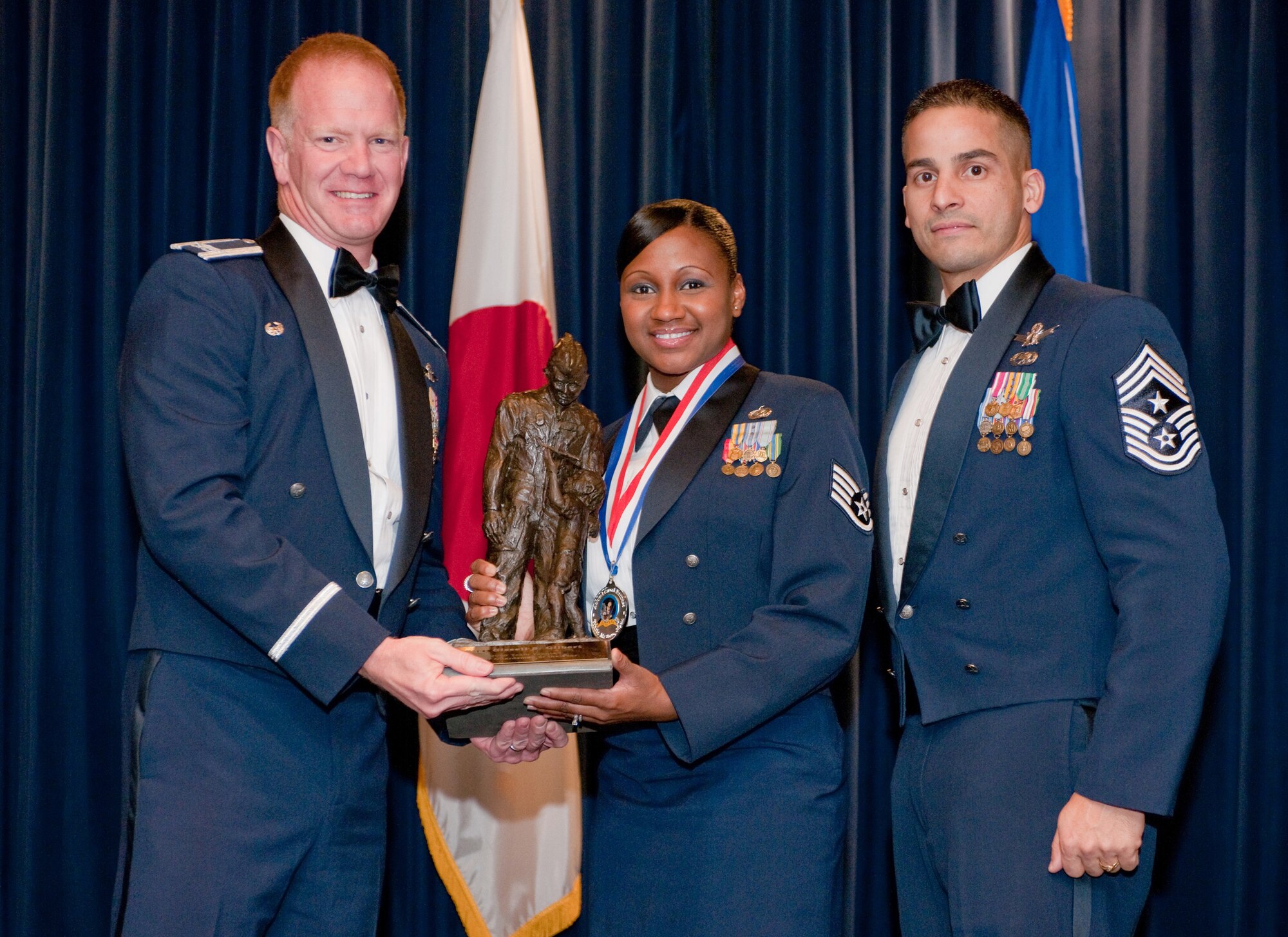 YOKOTA AIR BASE, Japan -- Col. J. Marcus Hicks, 374th Airlift Wing commander, and Chief Master Sgt. Benjamin Caro Jr., 374th AW command chief master sergeant, presents Staff Sgt. Gissell Gilbert, center, with the Honor Guard of the Year award Feb. 3. Sgt. Gilbert is assigned to the 374th Operation Group. (U.S. Air Force photo/Osakabe Yasuo)