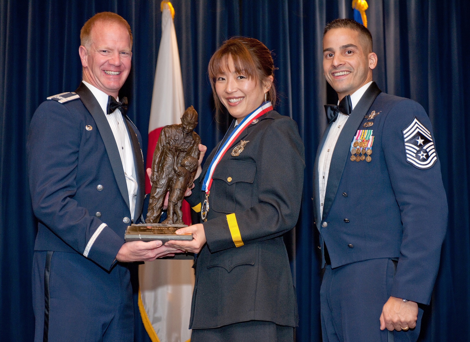 YOKOTA AIR BASE, Japan -- Col. J. Marcus Hicks, 374th Airlift Wing commander, and Chief Master Sgt. Benjamin Caro Jr., 374th AW command chief master sergeant, presents Ms. Chinatsu Kano, center, with the US/JN Civilian Category I award Feb. 3. Ms. Kano is assigned to the 374th Civil Engineer Squadron. (U.S. Air Force photo /Osakabe Yasuo)