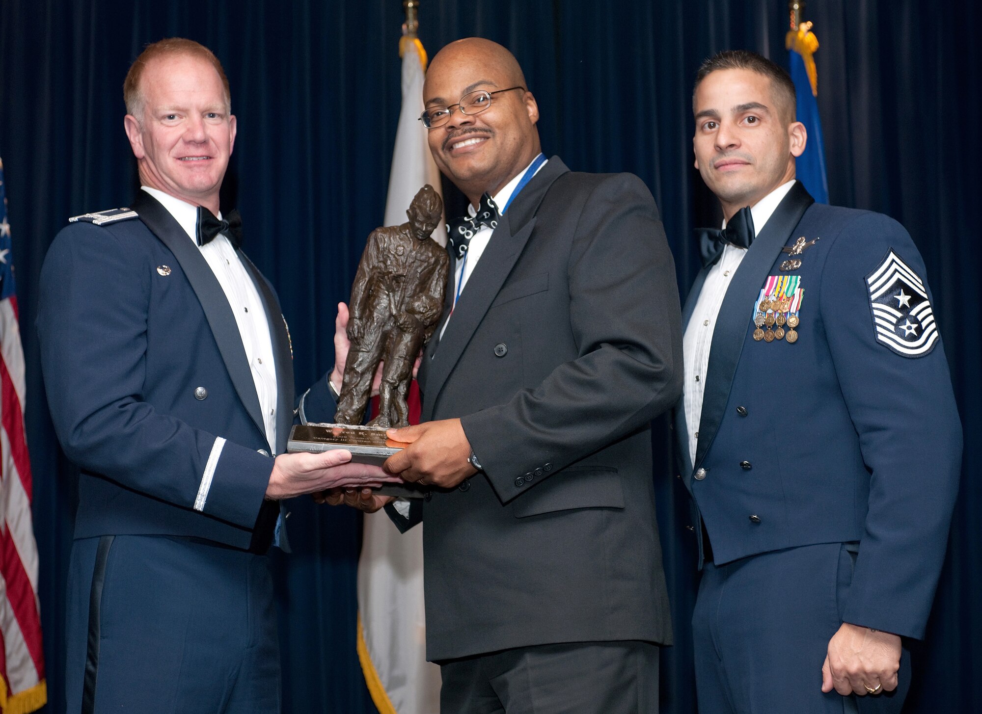 YOKOTA AIR BASE, Japan -- Col. J. Marcus Hicks, 374th Airlift Wing commander, and Chief Master Sgt. Benjamin Caro Jr., 374th AW command chief master sergeant, presents Mr. Wilfred Smith, center, with the US/JN Civilian Category III award Feb. 3. Mr. Smith is assigned to the 374th Operation Support Squadron. (U.S. Air Force photo/Osakabe Yasuo)