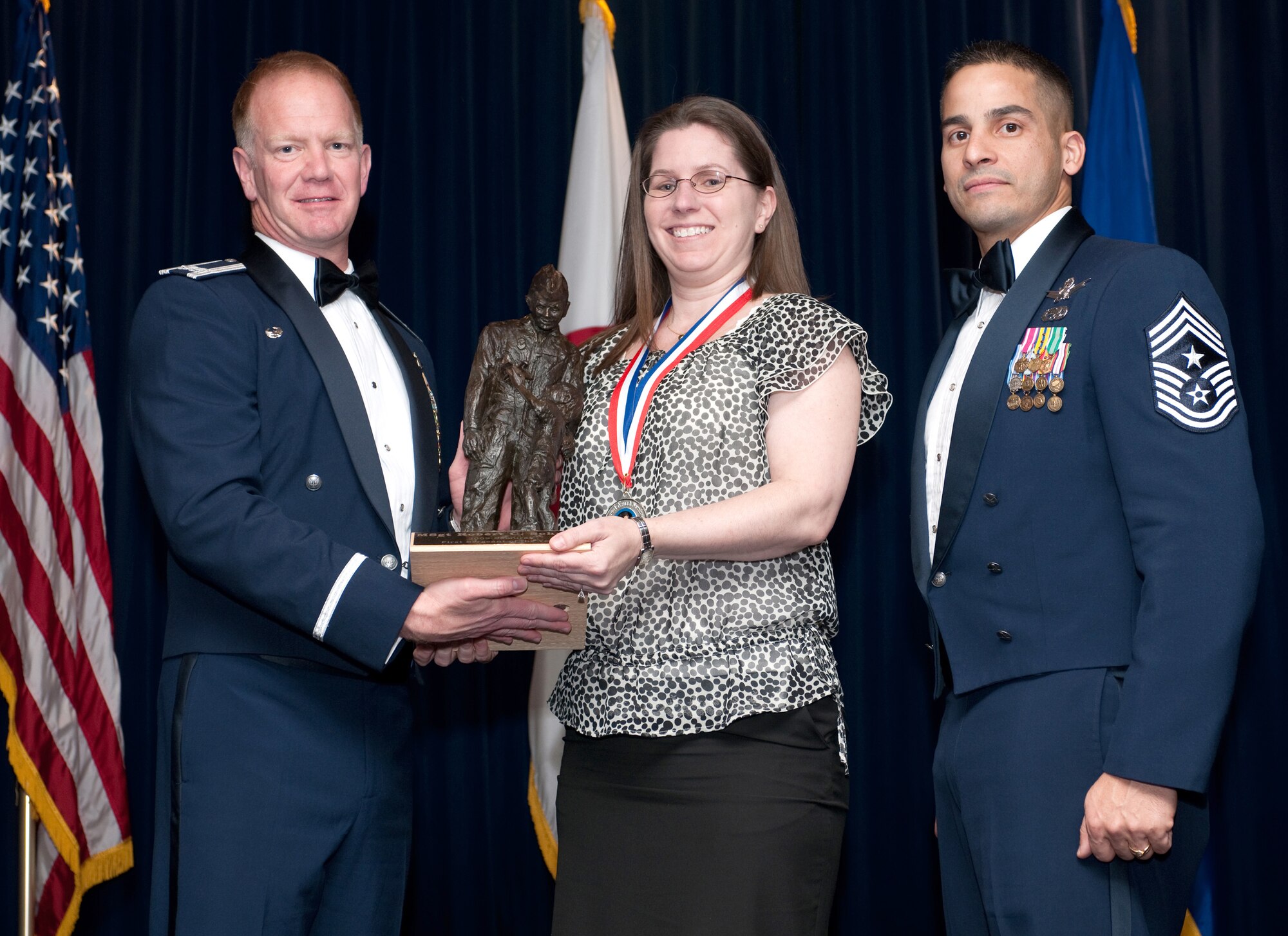 YOKOTA AIR BASE, Japan -- Col. J. Marcus Hicks, 374th Airlift Wing commander, and Chief Master Sgt. Benjamin Caro Jr., 374th AW command chief master sergeant, presents Mrs. Sindy Shultz, center, wife of Master Sgt. Robert Schultz with the First Serguant of the Year award. Master Sgt. Schultz is assigned to the 374th Mission Support Group. (U.S. Air Force photo/Osakabe Yasuo)
