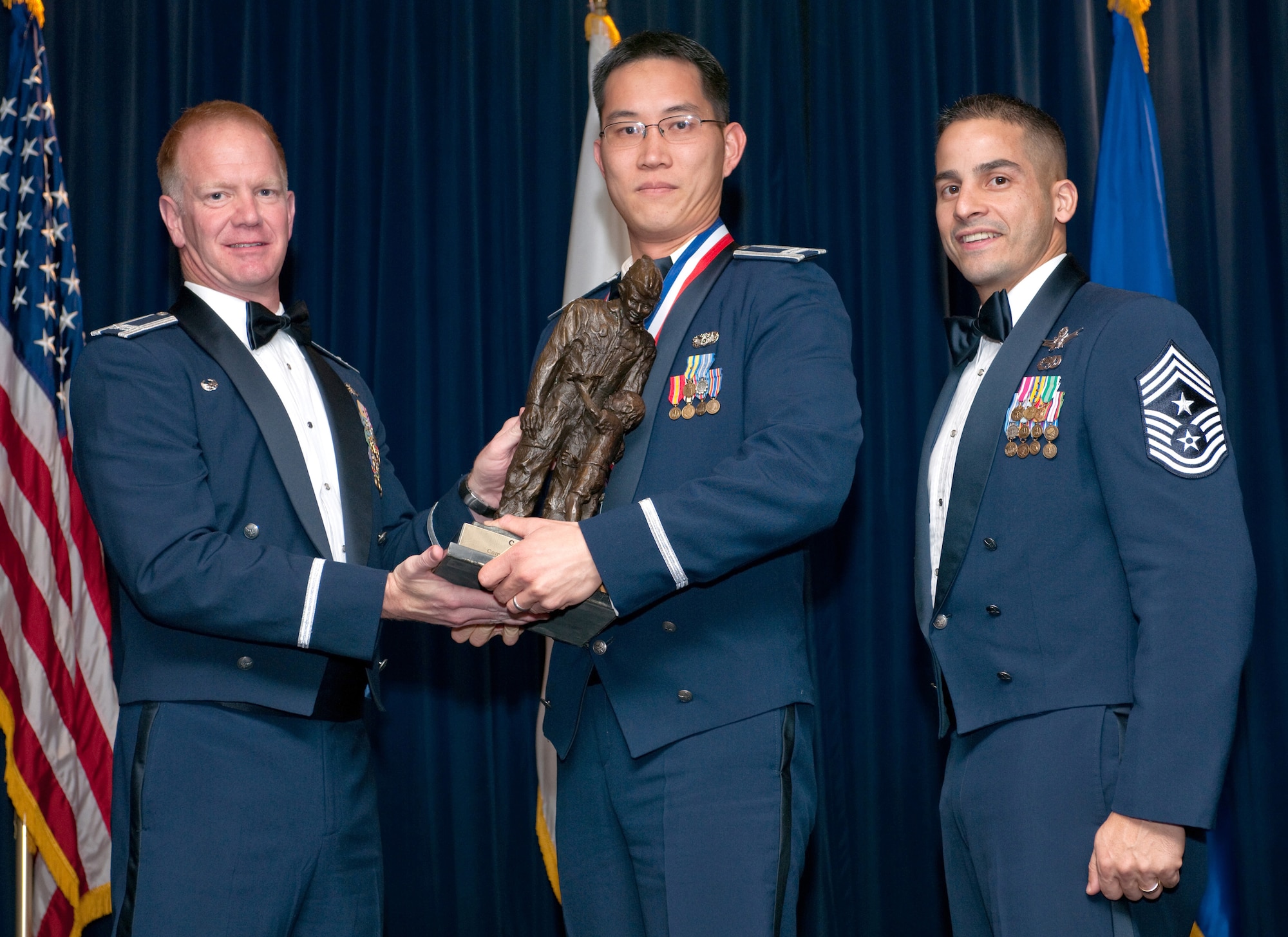 YOKOTA AIR BASE, Japan -- Col. J. Marcus Hicks, 374th Airlift Wing commander, and Chief Master Sgt. Benjamin Caro Jr., 374th AW command chief master sergeant, presents Capt. Ricky Cam, center, with the Kensei Company-grade officer of the Year award Feb. 3. Capt. Cam is assigned to the 5th Air Force. (U.S. Air Force photo/Osakabe Yasuo)