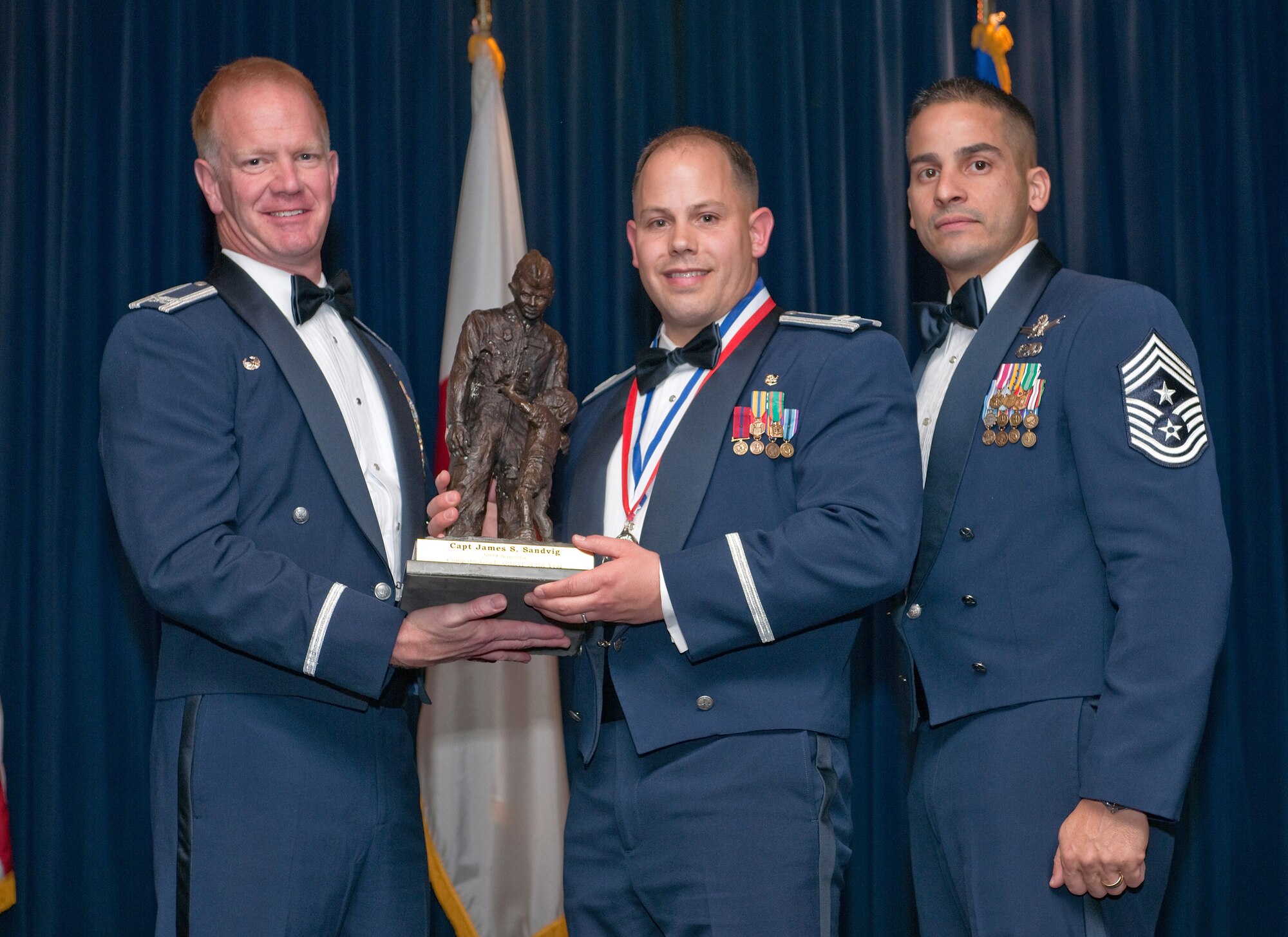 YOKOTA AIR BASE, Japan -- Col. J. Marcus Hicks, 374th Airlift Wing commander, and Chief Master Sgt. Benjamin Caro Jr., 374th AW command chief master sergeant, presents Capt. James Sandvig with the Company-grade officer of the Year award Feb. 3. Capt. Sandvig is assigned to the  374th Medical Group. (U.S. Air Force photo/Osakabe Yasuo)