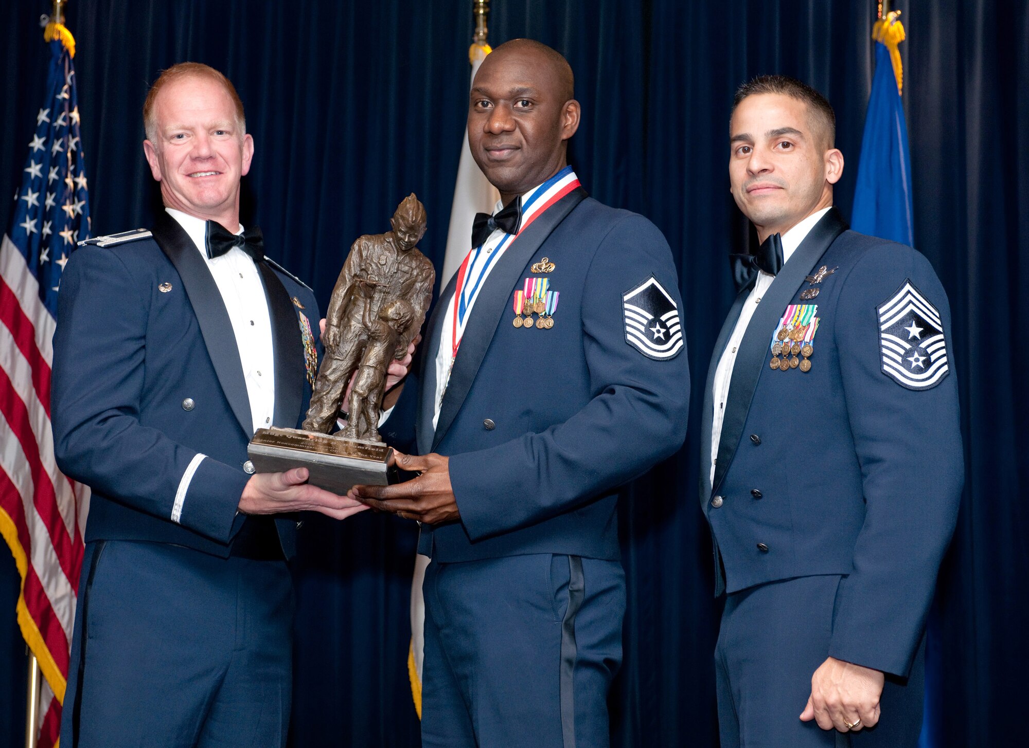 YOKOTA AIR BASE, Japan -- Col. J. Marcus Hicks, 374th Airlift Wing commander, and Chief Master Sgt. Benjamin Caro Jr., 374th AW command chief master sergeant, presents Master Sgt. Quardrick Brumfield, center,  with the Senior Non Commissioned Officer of the Year award Feb. 3. Sgt. Brumfield is assigned to the 374th Mission Support Group. (U.S. Air Force photo/Osakabe Yasuo)