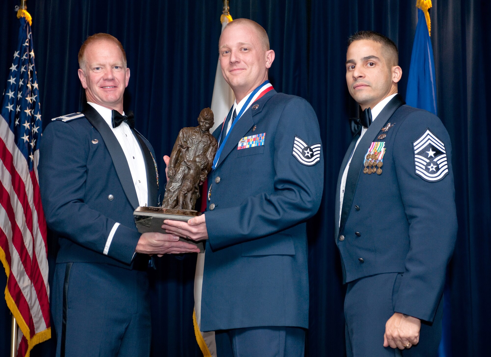 YOKOTA AIR BASE, Japan -- Col. J. Marcus Hicks, 374th Airlift Wing commander, and Chief Master Sgt. Benjamin Caro Jr., 374th AW command chief master sergeant, presents Technical Sgt. Thomas Hall, center, with the Samurai Non- Commissioned Officer of the Year award, Feb 3. Sgt. Hal is assigned to the 374th Medical Group. (U.S. Air Force photo/Osakabe Yasuo)