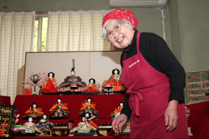 Kikuko Shinjo, caretaker at the Iwakuni Youth Hostel, shared laughs with the small class as she gave a brief history lesson about the Hina Dolls and their significance to Japanese culture Feb. 16. Most households annually display hina-ningyo, which are special dolls or sets of dolls staged upon a red-carpeted stand with five or seven steps, during the birth or celebration of a young girl.