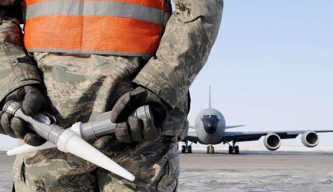 U.S. Air Force Senior Airman James Partin, 376th Expeditionary Aircraft Maintenance Squadron instrument and flight control systems technician, stands by in preparation to marshal a KC-135 Stratotanker to the taxiway before take-off from the Transit Center at Manas, Kyrgyzstan, Feb. 16, 2010. Due to the fuel the Transit Center provides, Fighters, bombers and other combat support aircraft provide overwatch for troops on the ground, protecting the war fighters and deterring the enemy.  (U.S. Air Force photo/Senior Airman Nichelle Anderson/released