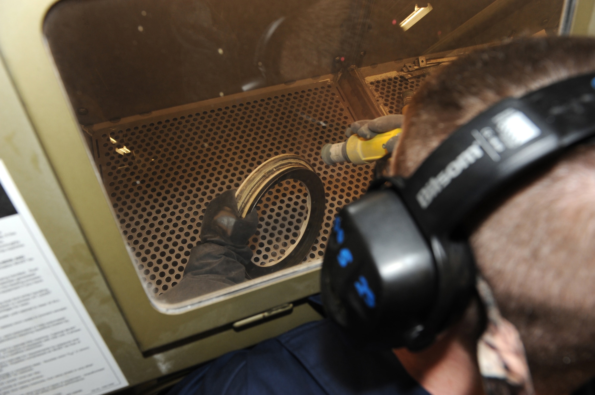 WHITEMAN AIR FORCE BASE, Mo. - Senior Airman Eric Pearl, 509th Aircraft Maintenance Squadron wheel and tire shop, prepares to media blast a piece of a wheel from a T-38, Feb. 16, 2010. Media blasting removes foreign material and paint that is stuck to the part. (U.S. Air Force photo/Airman 1st Class Carlin Leslie)