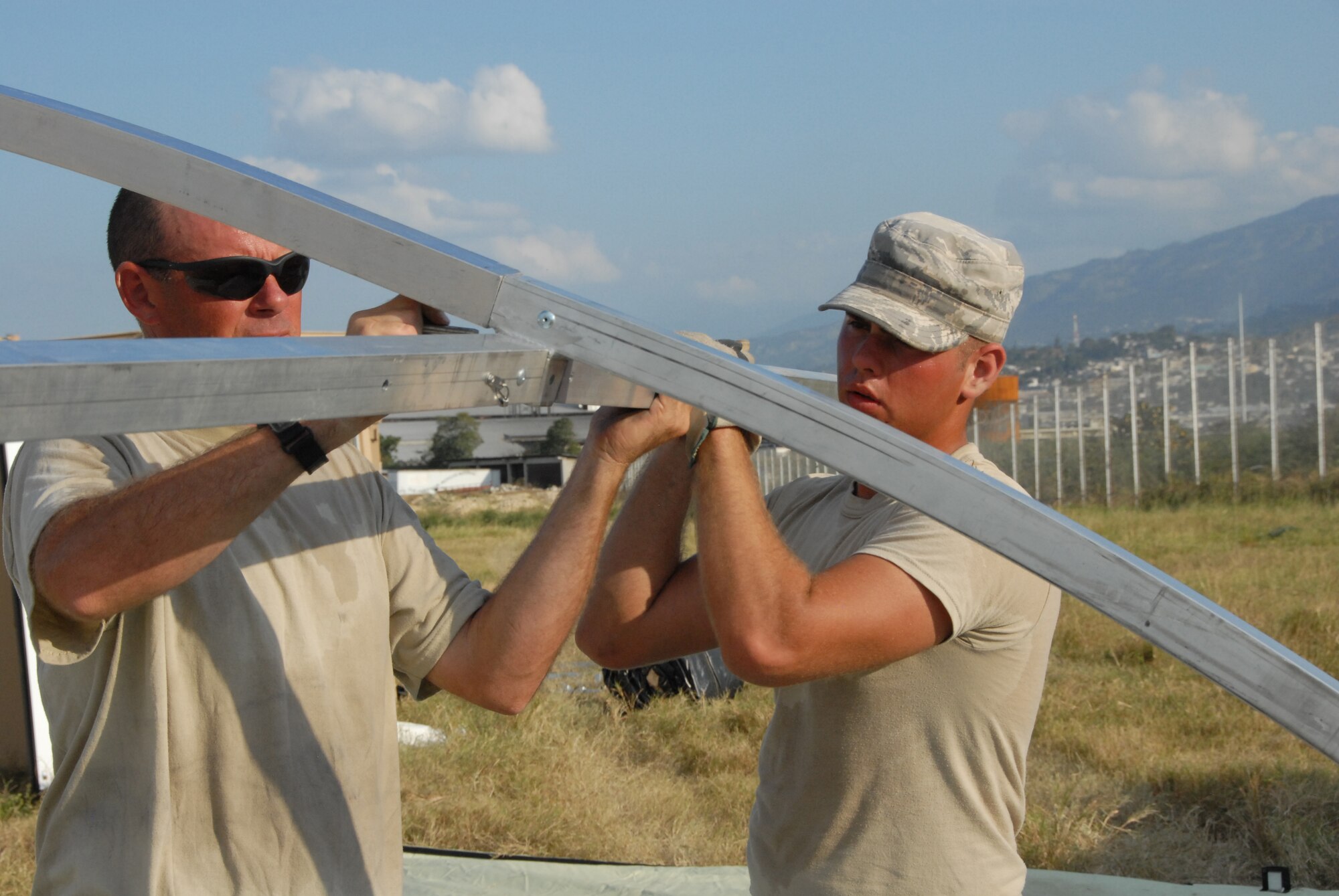 Master Sgt. Casey Batterton (left) and Senior Airman Mike Stroebel build the frame for tents that will house medical workers. The tents are built on the EMEDS site, which will support 24 hour medical operations.