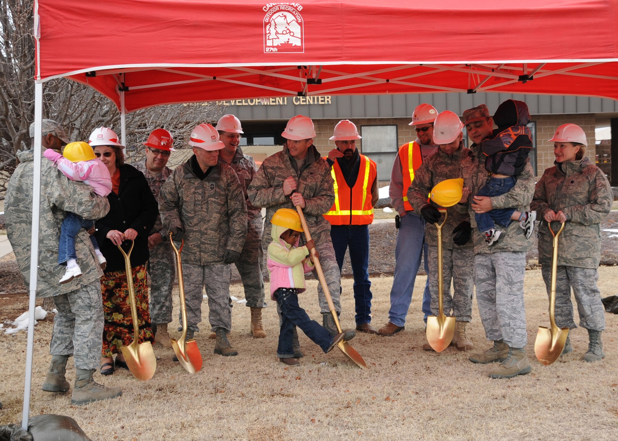 Col. Stephen Clark, 27th Special Operations Wing commander,  gets a helping hand from Ryienne Brown, daughter of Staff Sgt. Fabiola Brown, 27th Special Operations Wing Legal Office, during a groundbreaking for a new addition at the  Child Development Center Feb. 11. The renovated building at Cannon Air Force Base N.M., will include seven new classrooms, an updated kitchen, training areas and a reception area. (U.S. Air Force photo by Airman 1st Class Maynelinne De La Cruz)