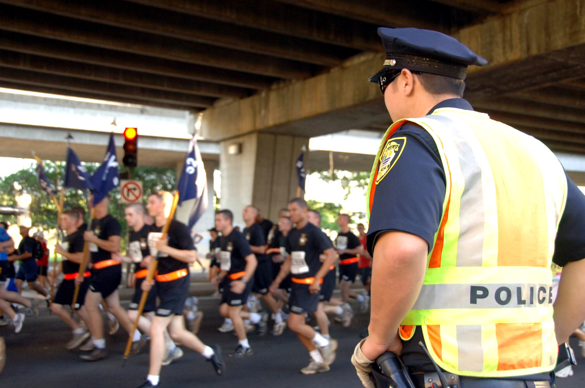 A Honolulu police officer ensures the safety of Great Aloha Run participants as they race toward the finish line Feb. 15. The run began at Aloha Tower, finished at Aloha Stadium, and boasted more than 17,000 participants. (U.S. Air Force photo by Senior Airman Nathan Allen)