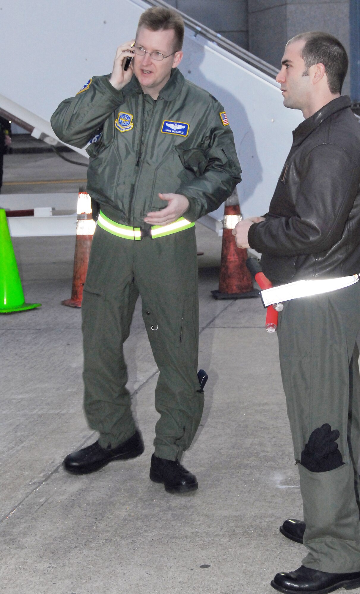 Lt. Col. John Donahue (left) makes a call shortly before the arrival of a C-17 Globemaster III transporting evacuees from Haiti to Charleston International Airport Feb. 9, 2010, in Charleston, S.C. Evacuee flights began arriving in Charleston Feb. 4, and the flights are currently being tracked by Colonel Donahue and four Air Force officers to provide flight information to civilian authorities in charge of repatriation efforts. Colonel Donahue is the 628th Air Base Wing chief of Wing Plans and was joined by 437th Airlift Wing Deputy Chief of Wing Plans Capt. Tony Mione (right) in greeting the evacuees on the airport parking ramp. (U.S. Air Force photo/Staff Sgt. Daniel Bowles)