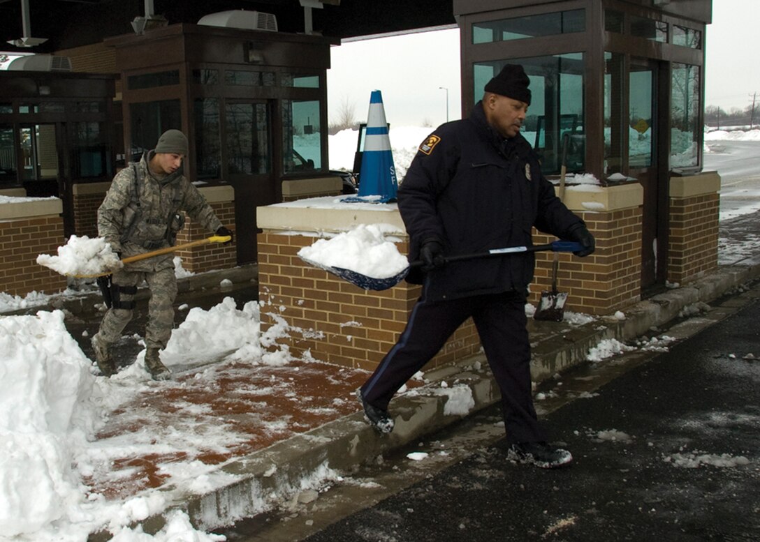Airman Vito Anzano, 316th Security Forces Squadron gate entry controller, and Lester Smith, Pinkerton Government Services security officer, clear snow from the Main Gate at Joint Base Andrews, Md., Feb. 9, 2010. (U.S. Air Force photo by Bobby Jones)