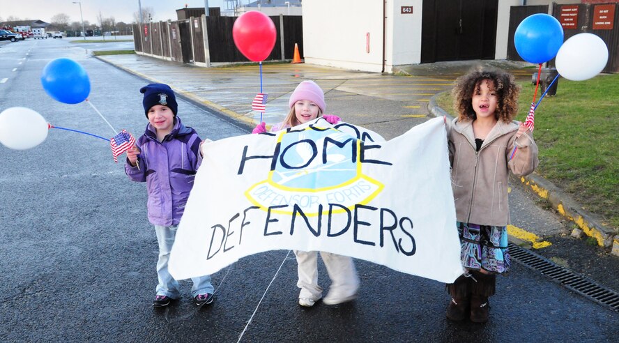 Hannah Hayes, left, 5, Macie Warnsing, center, 6, and Trinity Lansberry, 6, show off their 'Welcome Home Defenders' sign Feb. 13, while they wait for the 100th Security Forces Squadron Airmen to arrive home from their deployment to Iraq. (U.S. Air Force photo by Karen Abeyasekere)