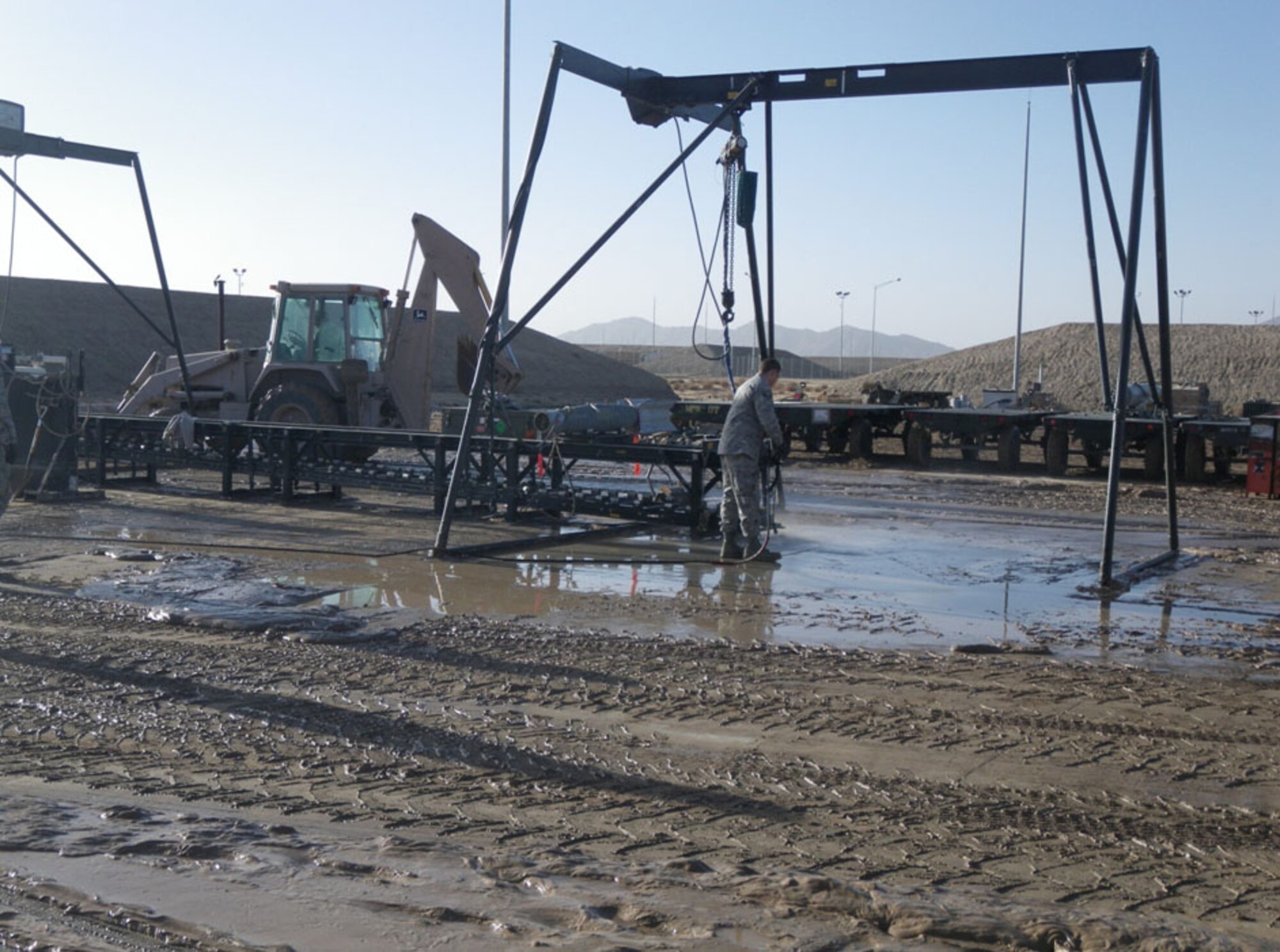 An Airman cleans up the Munitions Assembly Conveyer at Kandahar Airfield, Afghanistan. Two to six inches of mud covered the 451st Expeditionary Maintenance Squadron Munitions Flight’s Bomb Build Pad after the flash flood that occurred Feb. 8, 2010. (U.S. Air Force photo by Master Sgt. Matt McCullah/Released)