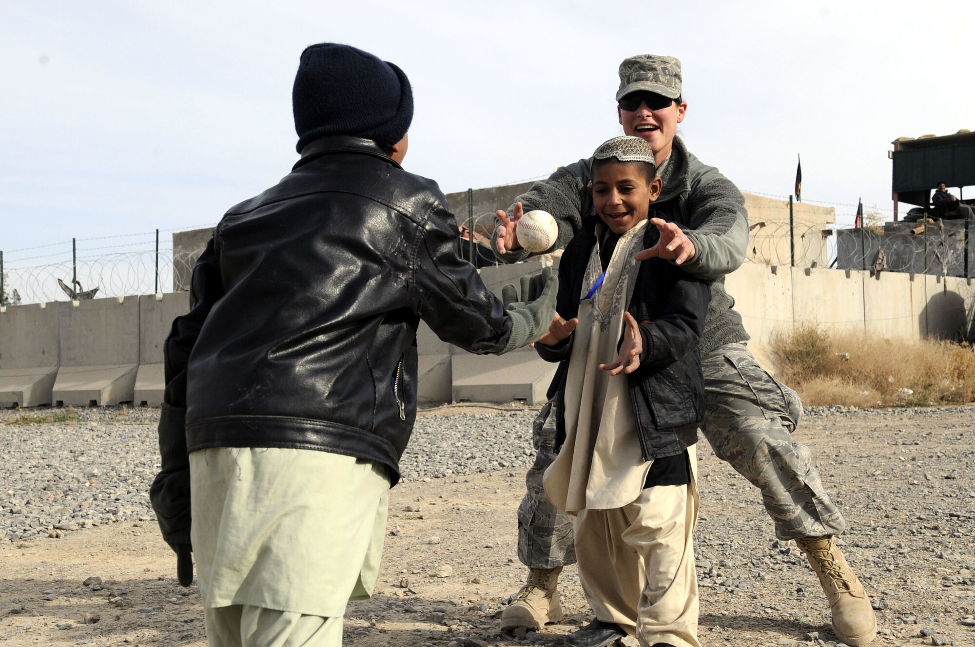 A volunteer from the 451st Air Expeditionary Wing plays catch with Afghan children at the Kandahar Airfield Bazaar School Feb. 15, 2010. The Bazaar School is a place where local Afghan children can play games and participate in activities with military members from Kandahar Airfield. (U.S. Air Force photo/Senior Airman Nancy Hooks/Released)