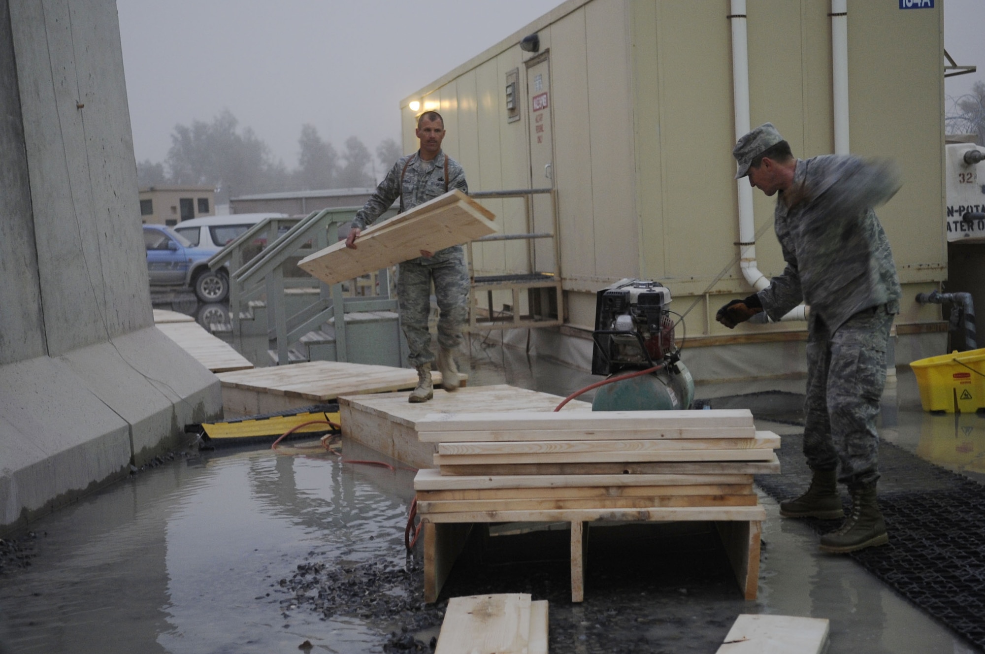 Chief Master Sgt. Steve McDonald, 451st Air Expeditionary Wing command chief, and Senior Master Sgt. George Gardner, 451st Expeditionary Civil Engineer Squadron, build a walkway for Camp Samek Airmen after the a flash flood occured here at Kandahar Airfield, Afghanistan, Feb. 8, 2010.  (U.S. Air Force photographer Senior Airman Nancy Hooks/Released)