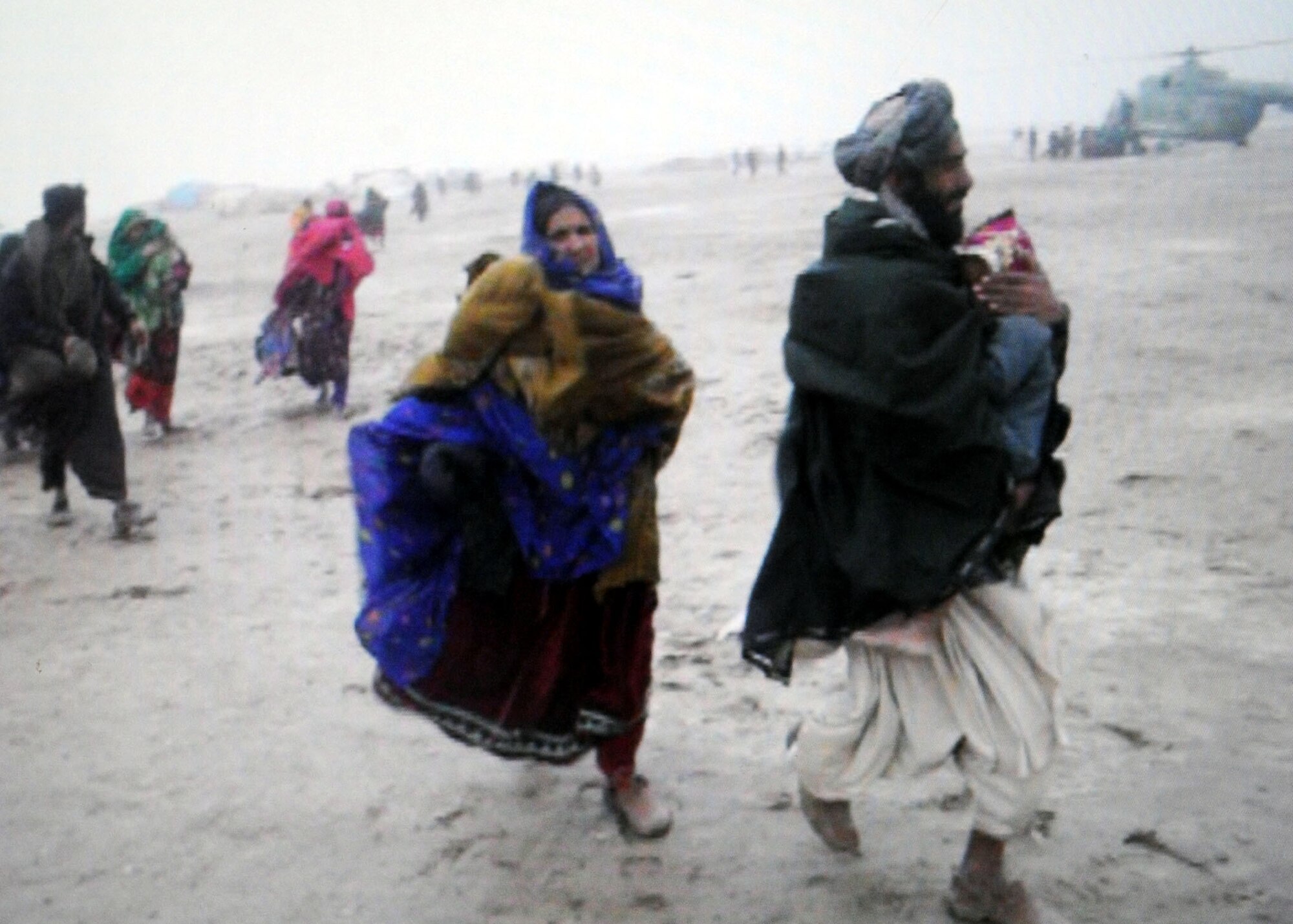 A snapshot of a video footage shows Afghan members of the nomadic Kuchi tribe running toward helicopters to be airlifted to a safe location as a flash flood nearly overtakes their village. Afghan National Army Air Corps servicemembers and their U.S. Air Force advisors rescued 83 Afghans during the humanitarian rescue mission Feb. 8, 2010. The group consisted mostly of women and children. (U.S. Air Force imagery by Lt. Col. Christopher Prejean/Released) 
