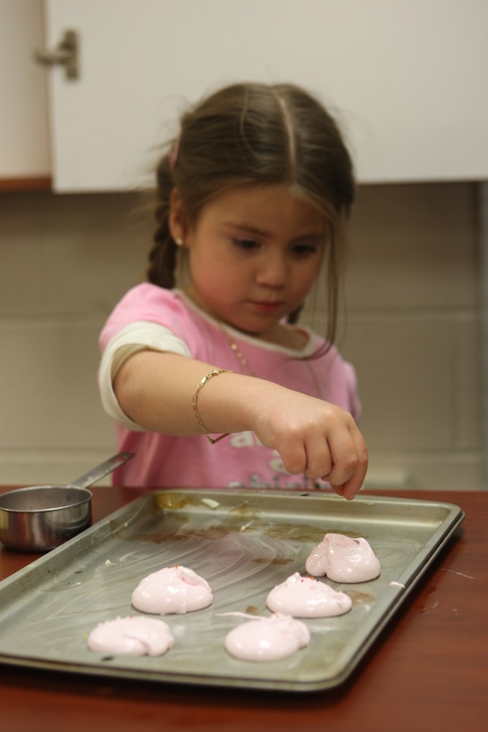 A young girl, age four, sprinkles jimmies over an icing mixture during the Candy School class at the Harriotte B. Smith library, Feb. 17. Participants learned to make caramel, master and divinity candy and boiled icing, all from scratch.