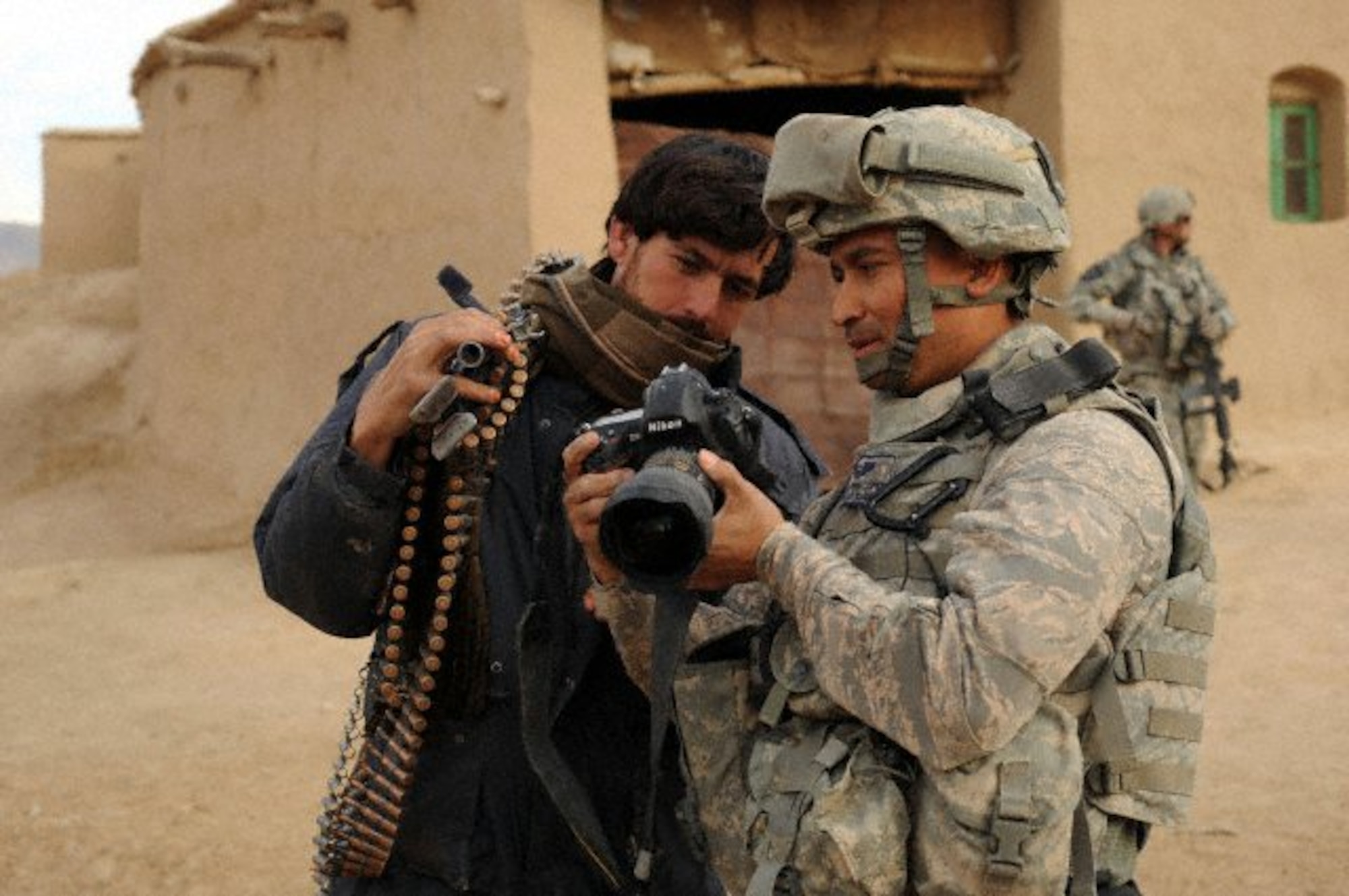 U.S. Air Force Tech. Sgt. Efren Lopez, 4th Combat Camera Squadron, shows digital photographs to an Afghan soldier in Shabila Kalan, Zabul province, Afghanistan. (U.S. Air Force photo by Staff Sgt. Christine Jones)

