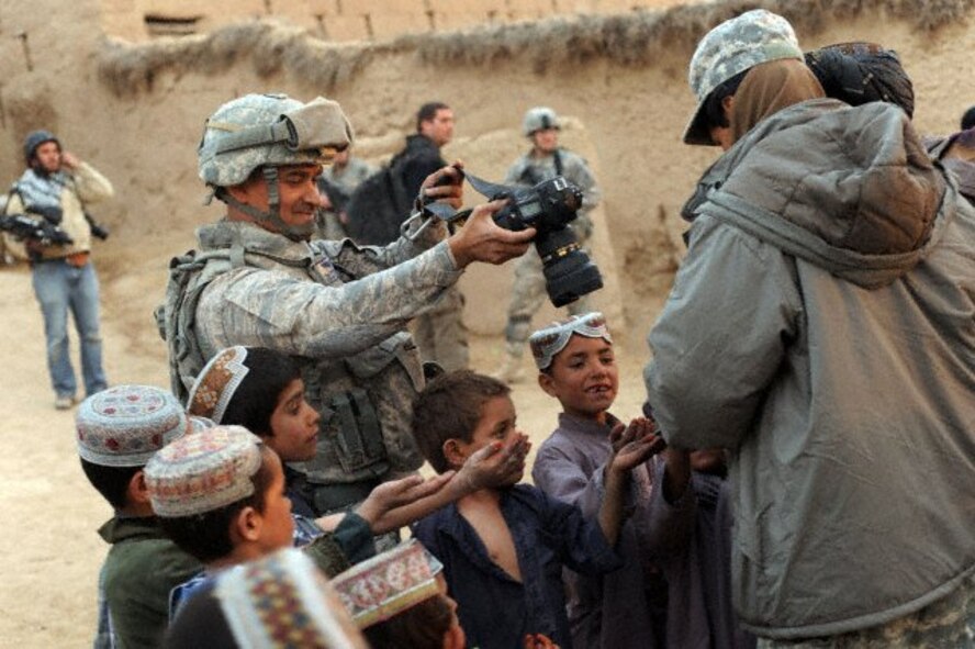 U.S. Air Force Tech. Sgt. Efren Lopez, 4th Combat Camera Squadron, takes a picture of Afghan children in Shabila Kalan, Zabul province, Afghanistan, Nov. 30, 2009. (U.S. Air Force photo by Staff Sgt. Christine Jones)

