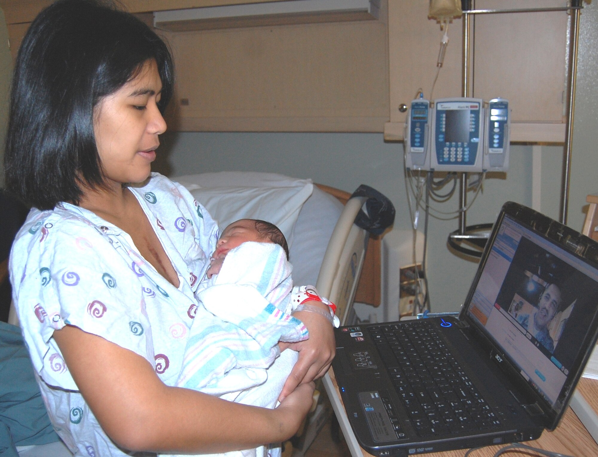 Kathy Forester holds son Brock Feb. 9 in Keesler Medical Center’s family birthing center as she talks with her husband Lerry, a master sergeant assigned to the 81st Medical Support Squadron.  He is currently on a six-month deployment  to  Kuwait and was unable to be present for Brock’s Feb. 8 birth.  Using teleconferencing equipment set up by the 81st MDSS medical information management flight, the couple was able see and talk to one another shortly after Brock’s birth.  Their first son was born at 7:34 a.m. weighing 7 pounds, 2.4 ounces and was 19 inches “tall.”  He joins sisters Madison, 2, and Kisha, 5.  Commenting on the video teleconference, Sergeant Forester exclaimed, “It was awesome — gotta love technology!  My wife was excited as I was.  I’m already looking forward to going home in five months.”  This is Sergeant Forester’s sixth deployment.  Looking forward to her husband’s return, Mrs. Forester told him, “It’ll be your turn to take care of the kids!”  (U.S. Air Force photo by Steve Pivnick)