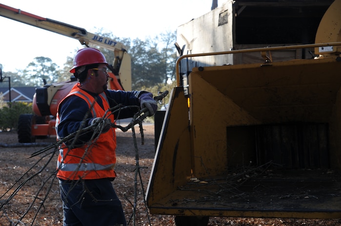 Tyler Huff places branches into a wood chipper on Joint Base Charleston Feb. 17 while performing grounds maintenance. The purpose of using the wood chipper is to keep bulk down and so the branches can later be reused as mulch. Mr. Huff is a member of the landscaping crew that works for Joppa Maintenance Company on the base. (U.S. Air Force photo/Senior Airman Katie Gieratz)(RELEASED)