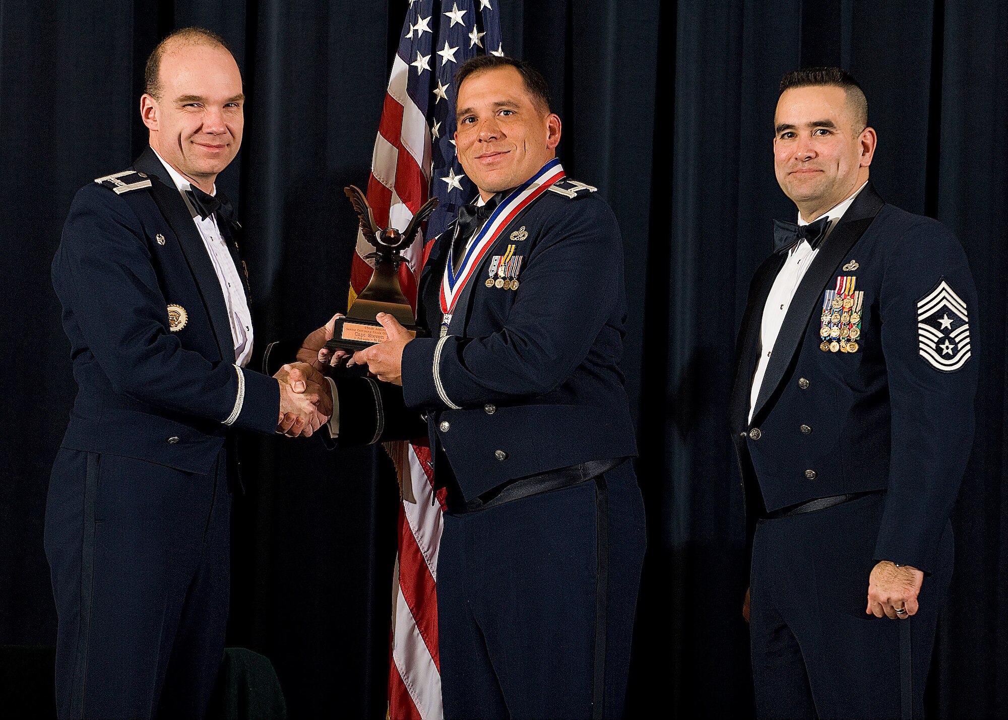 (Left) Col. Manson Morris, 436th Airlift Wing commander, and Chief Master Sgt. John Evalle, 436th AW command chief, present Capt. Steven Brown, 736th Aircraft Maintenance Squadron, with the award for Senior Company Grade Officer of the Year during the Annual Awards ceremony Feb. 12. (U.S. Air Force photo/Roland Balik)