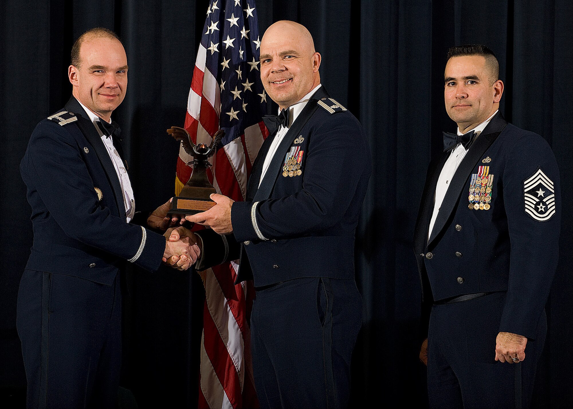 (Left) Col. Manson Morris, 436th Airlift Wing commander, and Chief Master Sgt. John Evalle, 436th AW command chief, present Lt. Col. William Peterson, 436th Aerial Port Squadron, with the award for First Sergeant of the Year during the Annual Awards ceremony Feb. 12. Colonel Peterson was accepting on behalf of Senior Master Sgt. Paul Hughes, 436th APS, who is currently deployed to Southwest Asia.  (U.S. Air Force photo/Roland Balik)