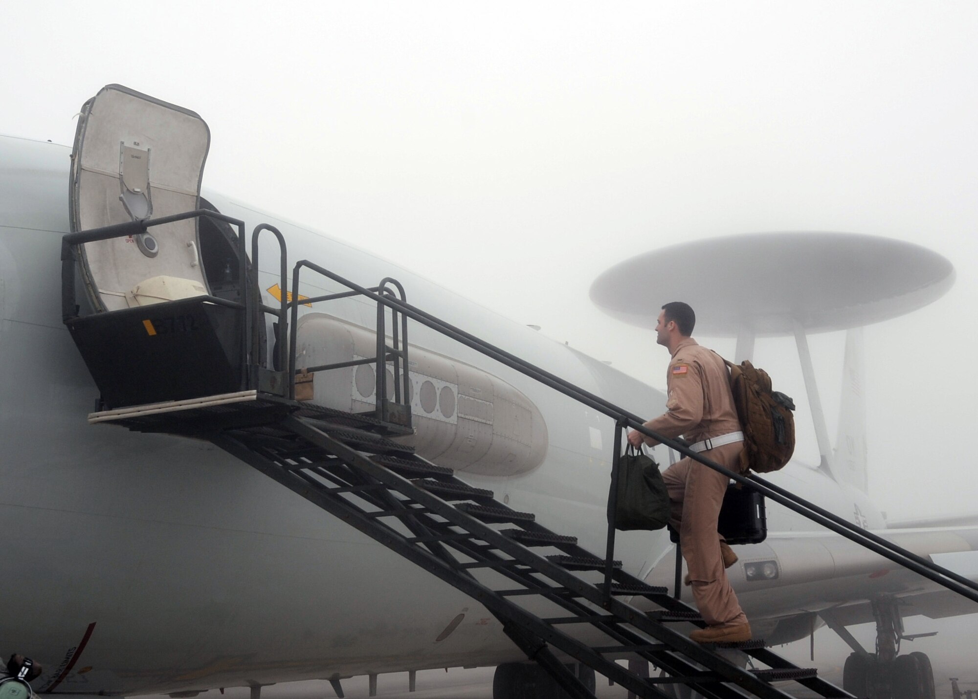 A flight crew member carries items into an E-3 Sentry Airborne Warning and Control System aircraft that is shrouded by fog on the flightline of the 380th Air Expeditionary Wing prior to a mission at a non-disclosed base in Southwest Asia on Feb. 16, 2010. The E-3, which is assigned to the 965th Expeditionary Airborne Air Control Squadron, is deployed from Tinker Air Force Base, Okla.  The 380th AEW supports operations Iraqi Freedom and Enduring Freedom and the Combined Joint Task Force-Horn of Africa.  (U.S. Air Force Photo/Master Sgt. Scott T. Sturkol/Released)