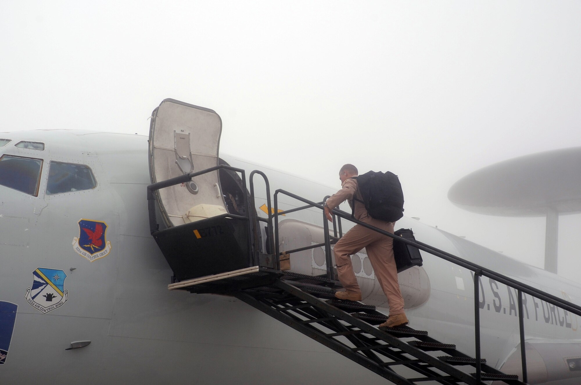 A flight crew member carries items into an E-3 Sentry Airborne Warning and Control System aircraft that is shrouded by fog on the flightline of the 380th Air Expeditionary Wing prior to a mission at a non-disclosed base in Southwest Asia on Feb. 16, 2010. The E-3, which is assigned to the 965th Expeditionary Airborne Air Control Squadron, is deployed from Tinker Air Force Base, Okla.  The 380th AEW supports operations Iraqi Freedom and Enduring Freedom and the Combined Joint Task Force-Horn of Africa.  (U.S. Air Force Photo/Master Sgt. Scott T. Sturkol/Released)