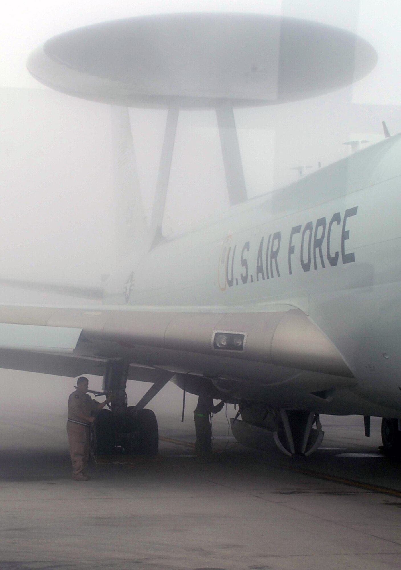 A flight crew members inspects an E-3 Sentry Airborne Warning and Control System aircraft that is shrouded by fog on the flightline of the 380th Air Expeditionary Wing at a non-disclosed base in Southwest Asia on Feb. 16, 2010. The E-3, which is assigned to the 965th Expeditionary Airborne Air Control Squadron, is deployed from Tinker Air Force Base, Okla.  The 380th AEW supports operations Iraqi Freedom and Enduring Freedom and the Combined Joint Task Force-Horn of Africa.  (U.S. Air Force Photo/Master Sgt. Scott T. Sturkol/Released)