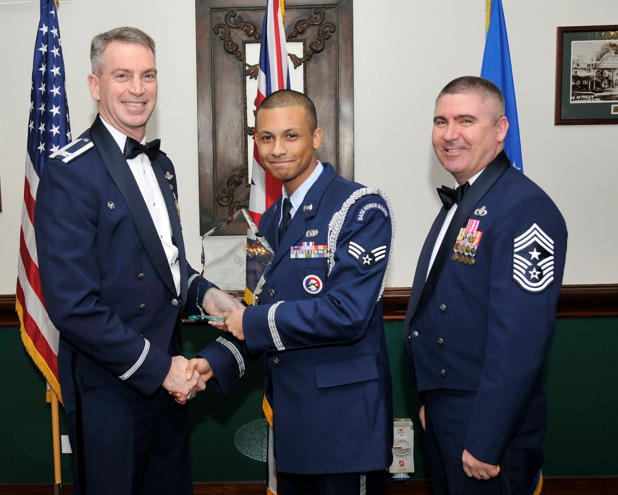 Col. Lawrence Reed, 48th Fighter Wing vice commander (left) and Chief Master Sgt. James Lucas present Senior Airman Marcello Robinson, 748th Aircraft Maintenance Squadron, with the award for Honor Guard Member of the Year at the annual awards at the Eagles Landing Feb 13. (U.S. Air Force photo by Airman 1st Class Eboni Knox)