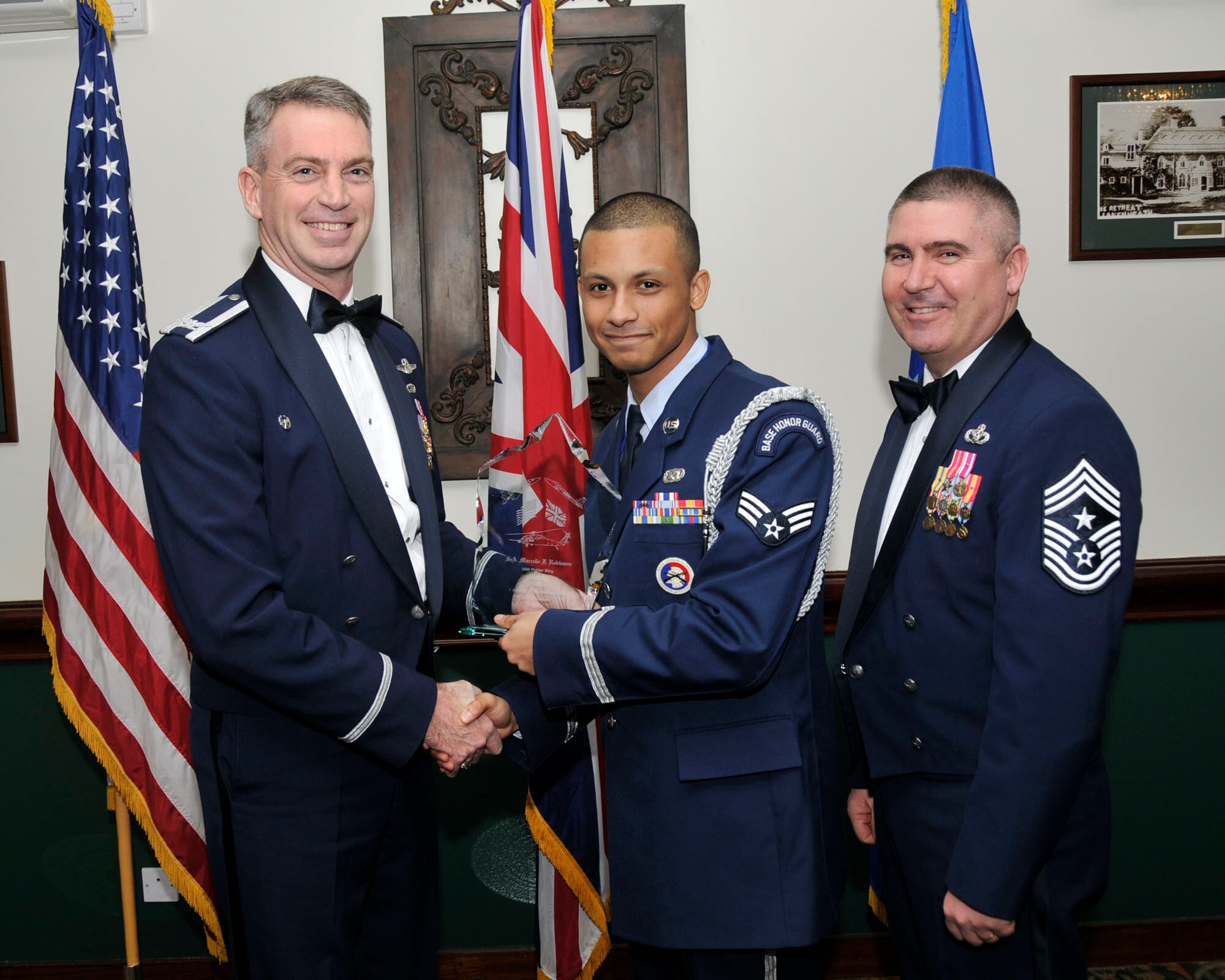 Col. Lawrence Reed, 48th Fighter Wing vice commander (left) and Chief Master Sgt. James Lucas present Senior Airman Marcello Robinson, 748th Aircraft Maintenance Squadron, with the award for Airman of the Year at the annual awards at the Eagles Landing Feb 13. (U.S. Air Force photo by Airman 1st Class Eboni Knox)