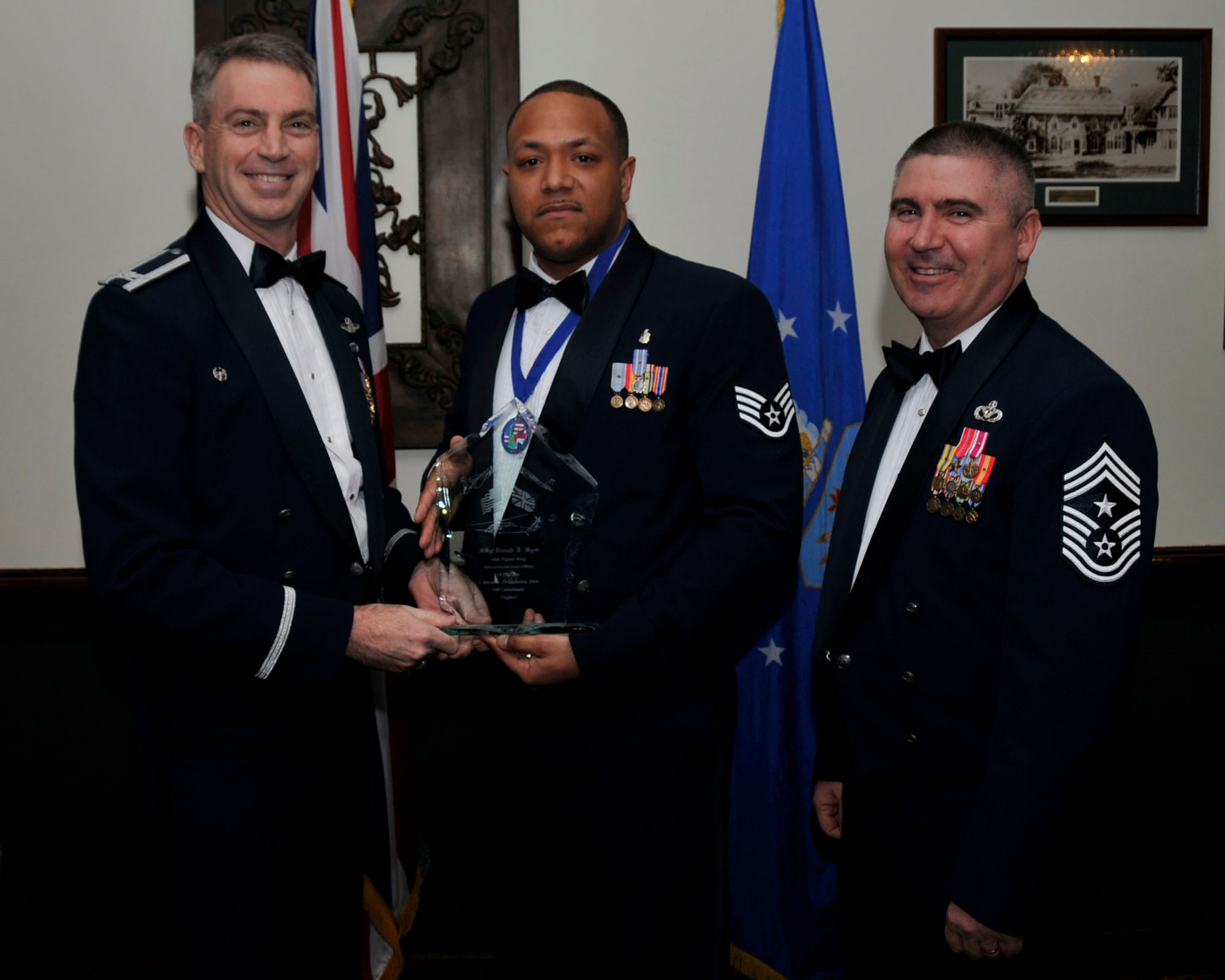 Col. Lawrence Reed, 48th Fighter Wing vice commander (left) and Chief Master Sgt. James Lucas present Staff Sgt. Donald J Byrd, 48th Medical Support Squadron, with the award for Non-Commissioned Officer of the Year at the annual awards at the Eagles Landing Feb 13. (U.S. Air Force photo by Airman 1st Class Eboni Knox)