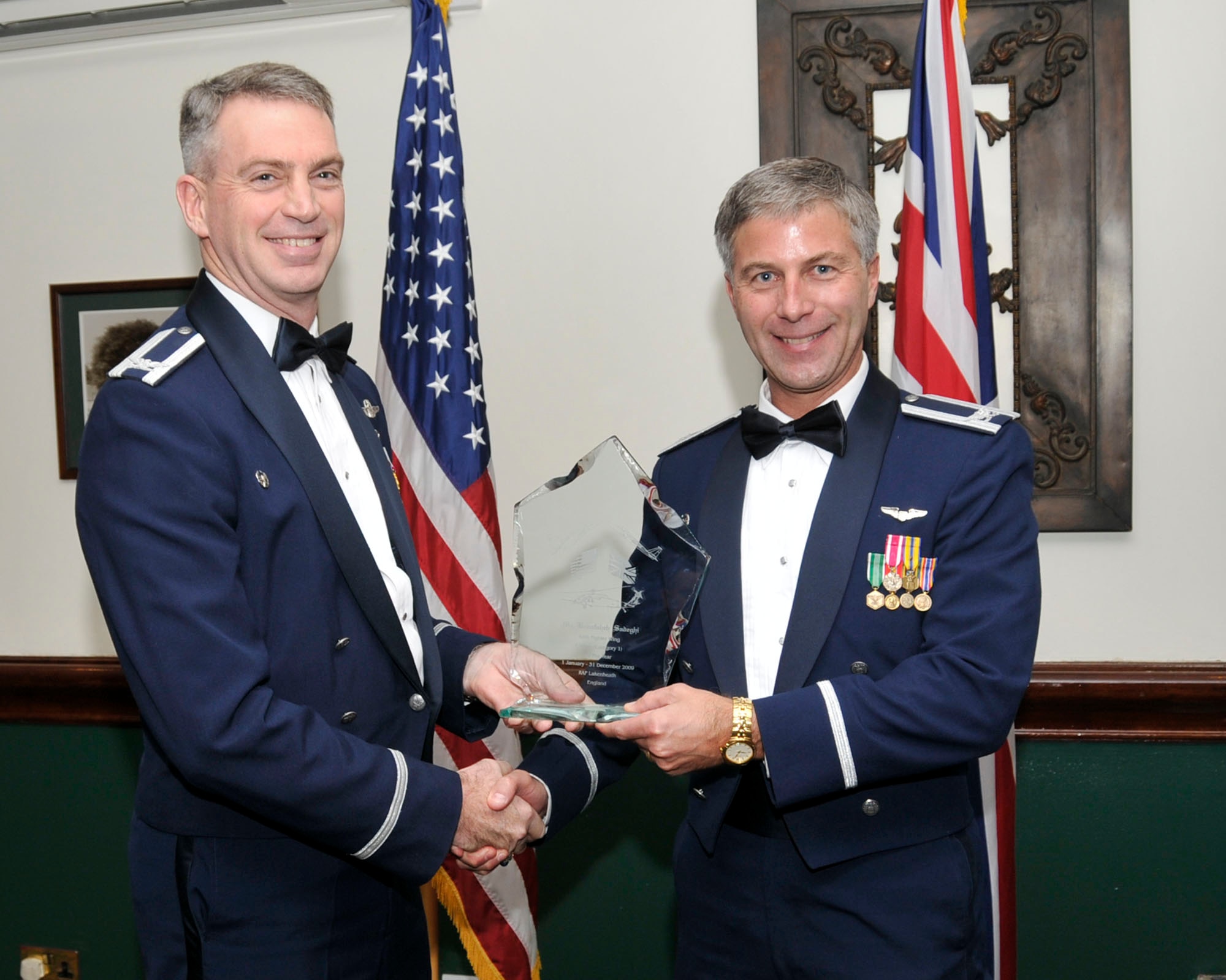 Col. Lawrence Reed, 48th Fighter Wing vice commander (left) and Chief Master Sgt. James Lucas present Col. Kenneth McDonnell, 48th Medical Group commander, on behalf of Ms. Banafsheh Sadeghi, 48th Aerospace Medicine Squadron, with the award for Civilian of the Year Category I at the annual awards at the Eagles Landing Feb 13. (U.S. Air Force photo by Airman 1st Class Eboni Knox)