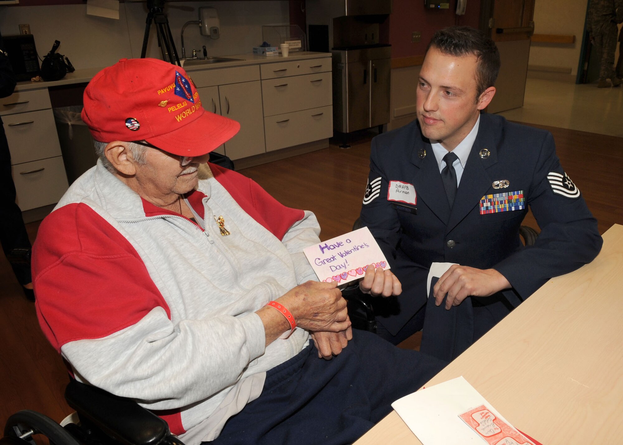 Tech. Sgt. Adam Morrison, 355th Logistics Readiness Squadron, hands a Valentine's Day card to Gilbert Quintanilla during the 35th Annual "National Salute to Veterans" event at the Southern Arizona VA Health Care System in Tucson. Mr. Quintanilla served for two years in the U.S. Marine Corps during World War II. Airmen from Davis-Monthan AFB were among hundreds of volunteers from the local area who showed their support and gratitude to Tucson's veterans. Volunteers also handed out thousands of home-made Valentine's Day cards that were sent to the veteran's hospital from children across the country. (U.S. Air Force photo/Airmen Jerilyn Quintanilla)
