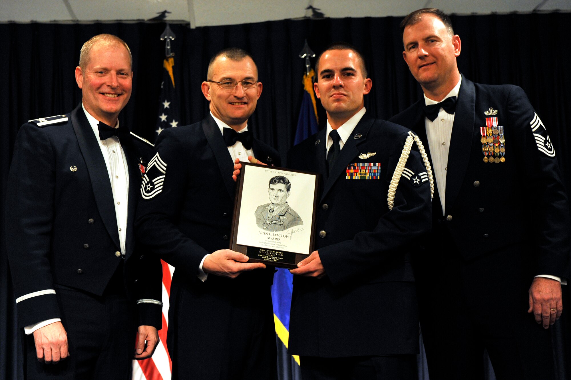Senior Airman Allen Plack, 53rd Airlift Squadron, receives the John Levitow Award from Col. Michael Zick, 19th Airlift Wing vice commander; Chief Master Sgt. John Craft, 19th Component Maintenance Squadron; and Chief Master Sgt. Jimmy Daniels, 19th Force Support Squadron; base leaders Feb. 16 during the Airman Leadership Class graduation ceremony. The Levitow Award is presented to the top graduate of each ALS class. (U.S. Air Force Photo by Senior Airman Christine Clark)