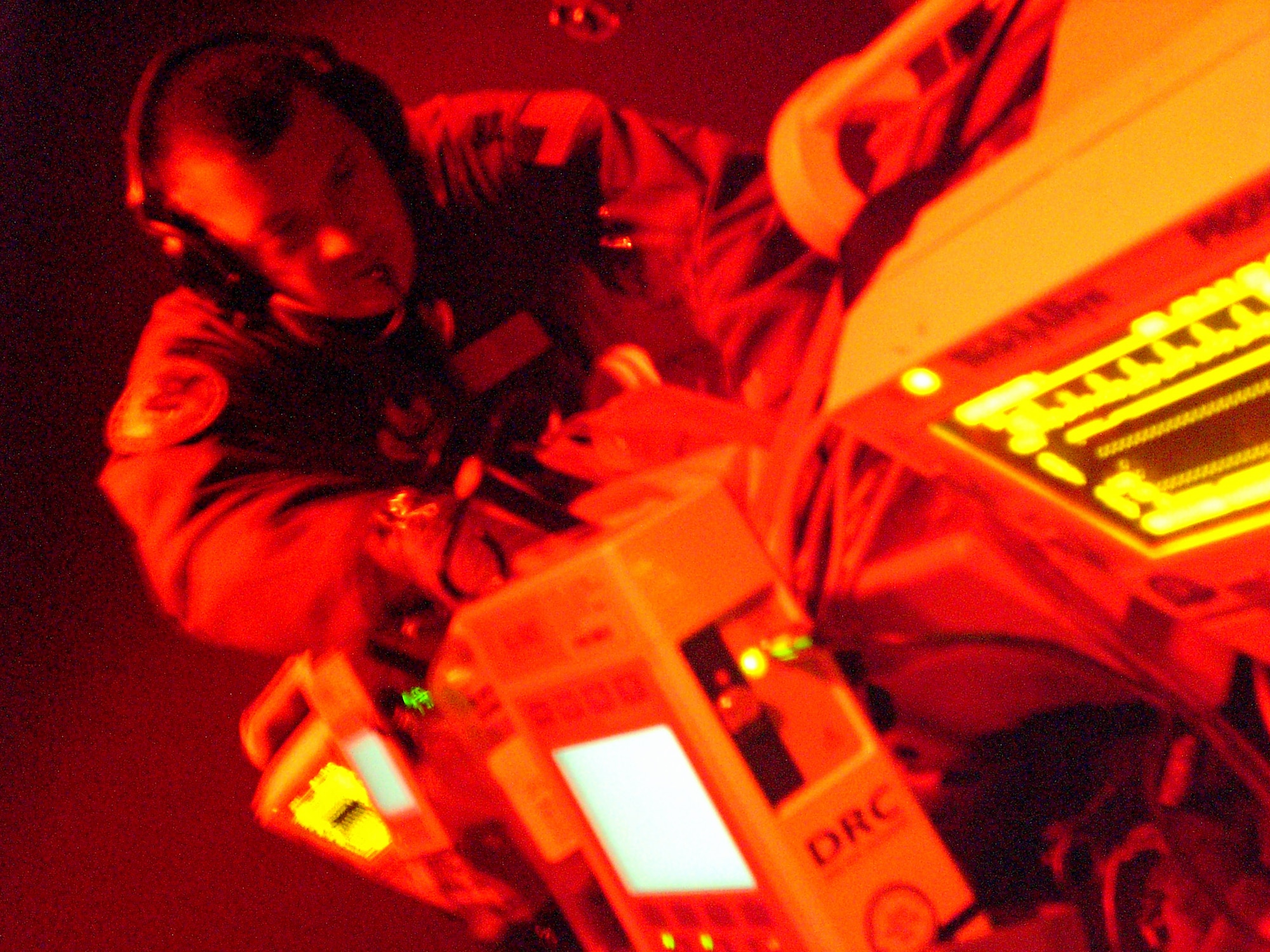Operating in the dim red glow simulating the back of a C-130 in flight, Capt. Derek Brumley checks equipment monitoring a critical care “patient.”  Capt. Brumley, a native of Barstow, Calif., is a critical care nurse and an instructor for the Air Force’s Centers for Sustainment of Trauma and Readiness Skills (CSTARS) at University Hospital Cincinnati, which trains Air Force critical care air transport team members. (U.S. Air Force photo/Derek Kaufman)