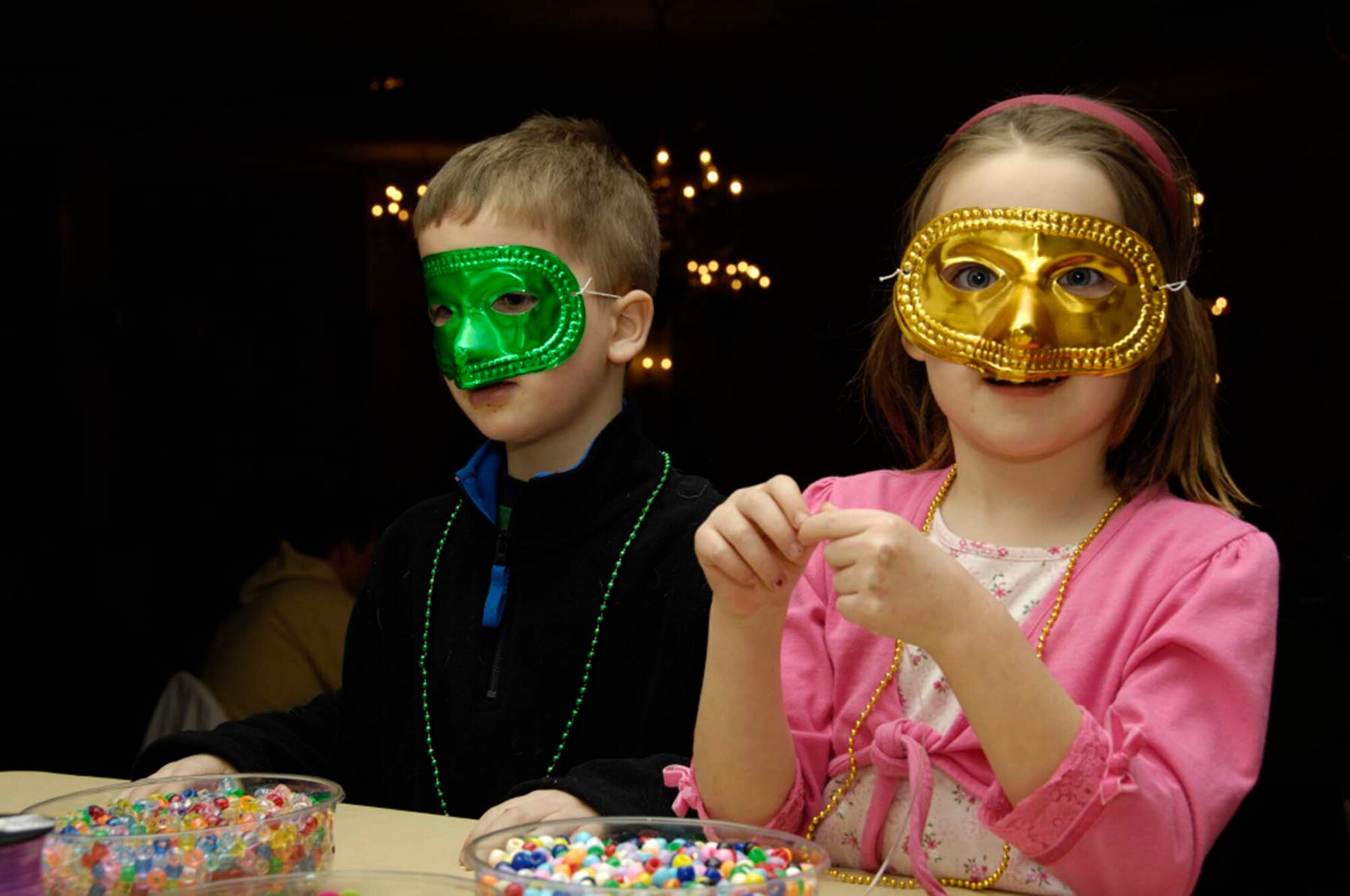 HANSCOM AIR FORCE BASE, Mass. – Appropriately masked for Mardi Gras Steak Night, Alexis and Colin Winn help out with preparing traditional Mardi Gras beads.  (U.S. Air Force photo by Linda LaBonte Britt)