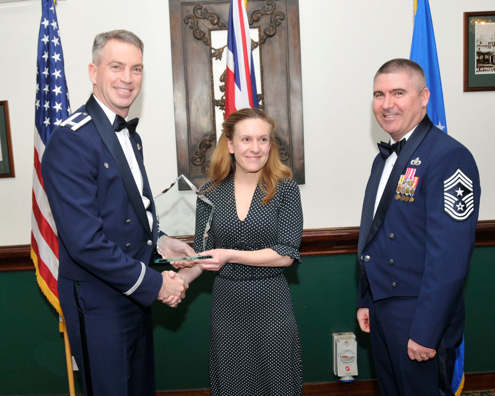 Col. Lawrence Reed, 48th Fighter Wing vice commander (left) and Chief Master Sgt. James Lucas present Ms. Miranda Firth, 48th Contracting Squadron, with the award for Civilian of the Year Category II at the annual awards at the Eagles Landing Feb 13. (U.S. Air Force photo by Airman 1st Class Eboni Knox)