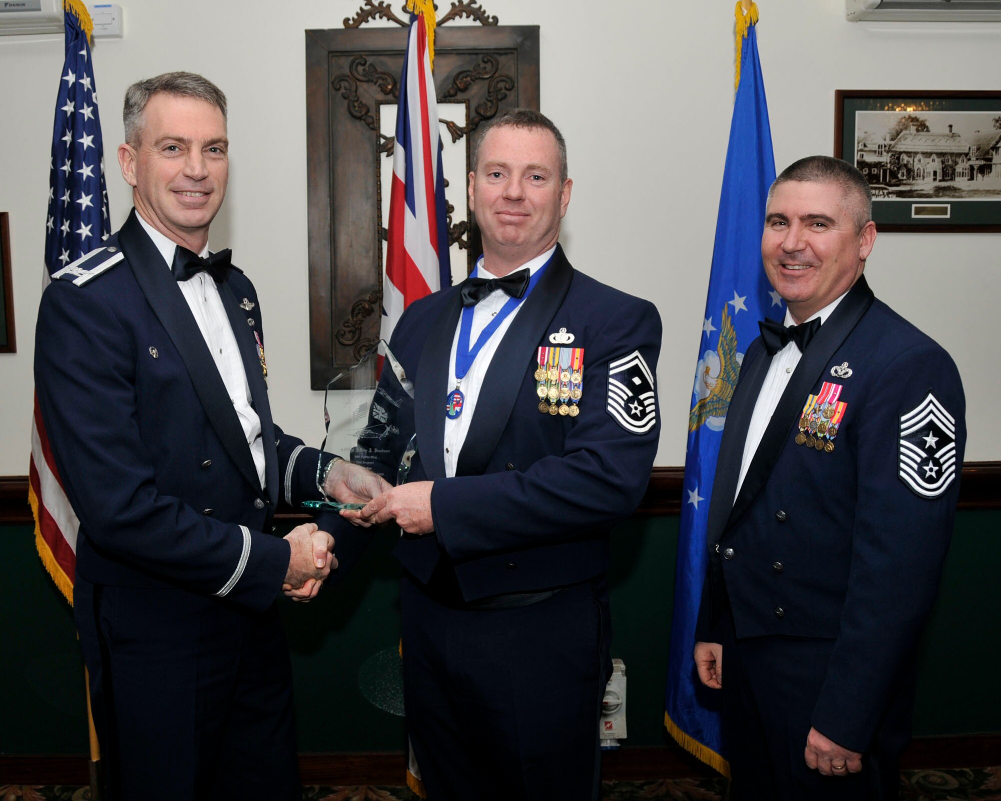 Col. Lawrence Reed, 48th Fighter Wing vice commander (left) and Chief Master Sgt. James Lucas present Senior Master Sgt.  Jeffrey J. Jacobson, 48th Security Forces Squadron, with the award for First Sergeant of the Year at the annual awards at the Eagles Landing Feb 13. (U.S. Air Force photo by Airman 1st Class Eboni Knox)