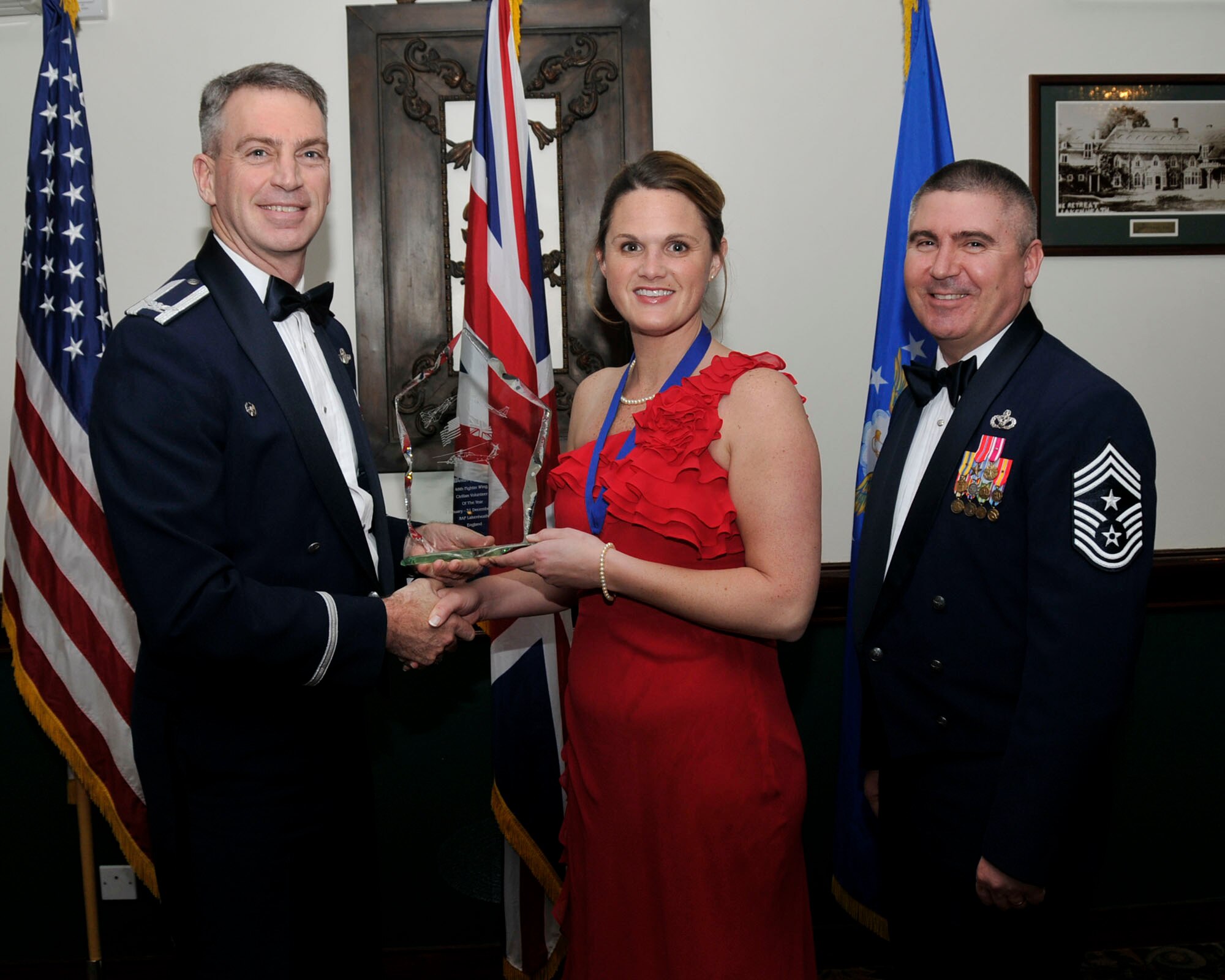 Col. Lawrence Reed, 48th Fighter Wing vice commander (left) and Chief Master Sgt. James Lucas present Ms. Wendi Lawlor, civilian volunteer of the year with the award at the annual awards at the Eagles Landing Feb 13. (U.S. Air Force photo by Airman 1st Class Eboni Knox)