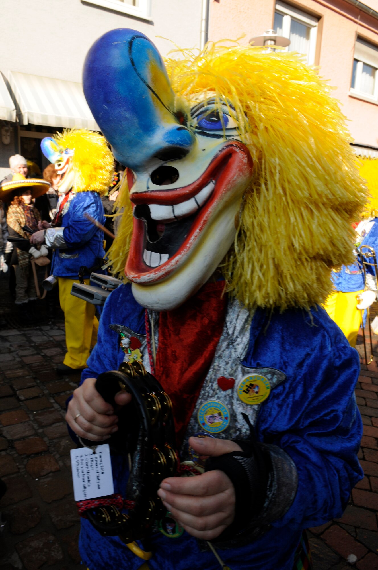 A local member dressed in a clown costume plays a tambourine during a Fasching parade, Ramstein Village, Germany, Feb. 16, 2010. This annual event is a pre-Lenten carnival which is celebrated with the donning of wild and fancy costumes to chase away the evil spirits of winter in preparation for spring. (U.S. Air Force photo by Airman 1st Class Brittany Perry)