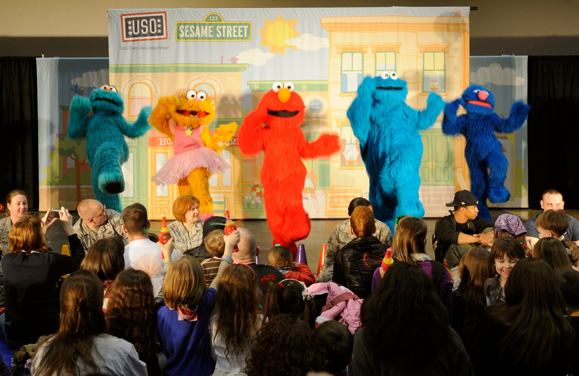 School age children enjoy a Sesame Street performance featuring five of the muppets in the base gym at Osan Air Base, Republic of Korea Feb. 12.  In January, the USO and Sesame Workshop kicked off “The Sesame Street/USO Experience for Military Families” tour. This year the tour will travel to Japan, Korea and Guam over the course of two months and deliver more family friendly shows tailored specifically for military families at 13 military installations.