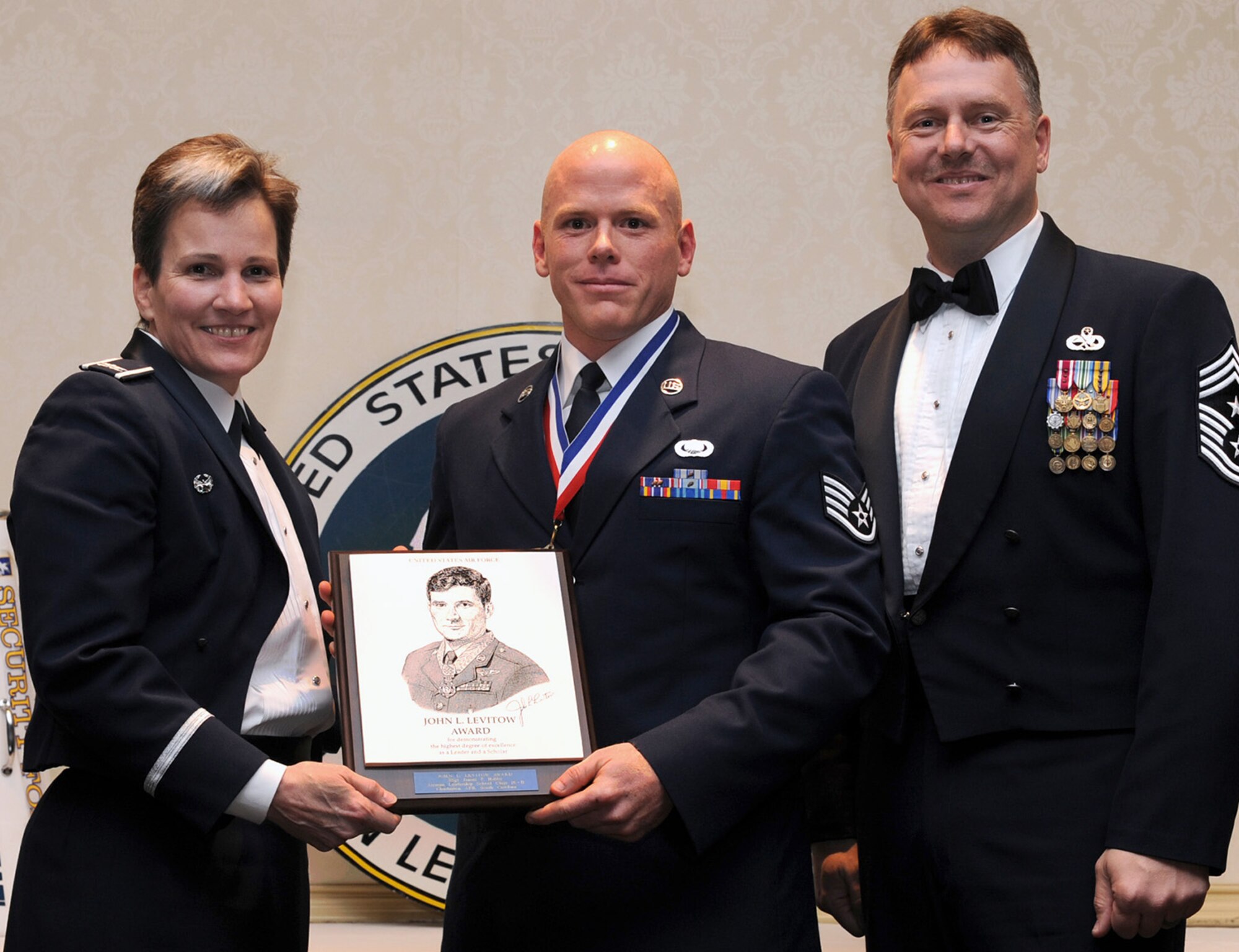 Col. Martha Meeker, left, and Chief Master Sgt. Mike Ivey, right, present Staff Sgt. James Hubby with the John L. Levitow Award during the Airman Leadership School Class 10-B graduation at the Charleston Club here Feb. 11. The award is given for a student's exemplary demonstration of excellence both as a leader and a scholar. Colonel Meeker is the 628th Air Base Wing commander, Chief Ivey is the 628th Air Base Wing command chief and Sergeant Hubby is a financial advisor with the 628th Comptroller Squadron. (U.S. Air Force photo/Senior Airman Katie Geiratz)